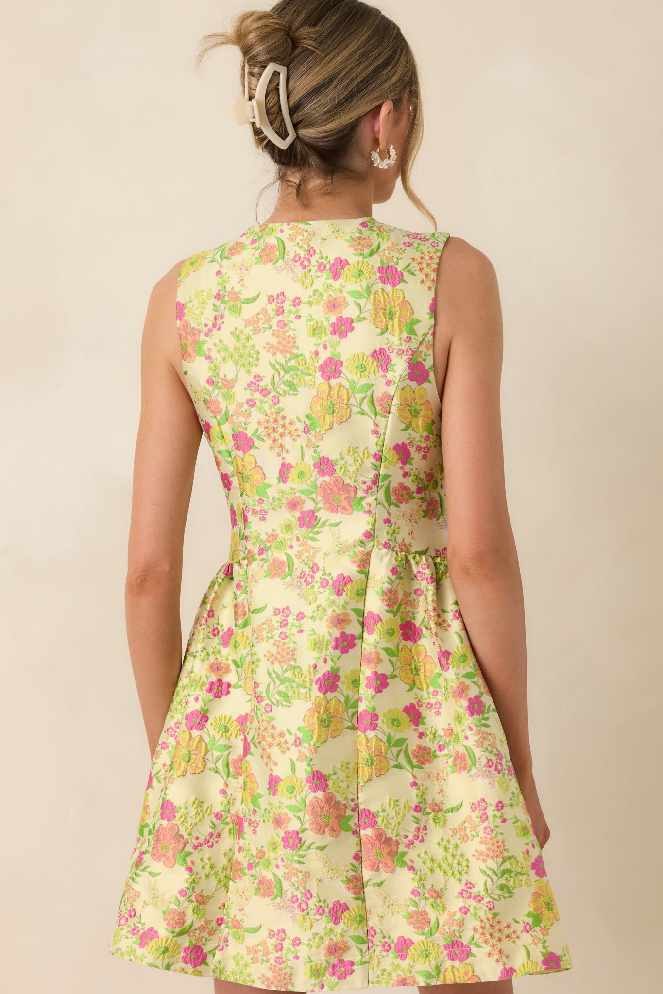 Back view of a sleeveless yellow floral mini dress with fitted bodice and softly flared A-line skirt.