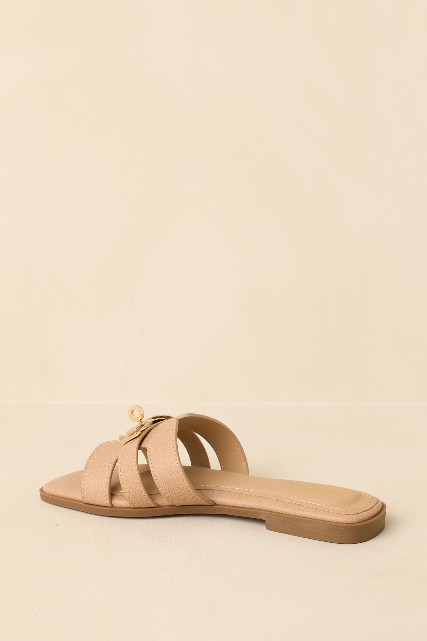Back view of beige slide sandals showing open heel and flat sole construction.