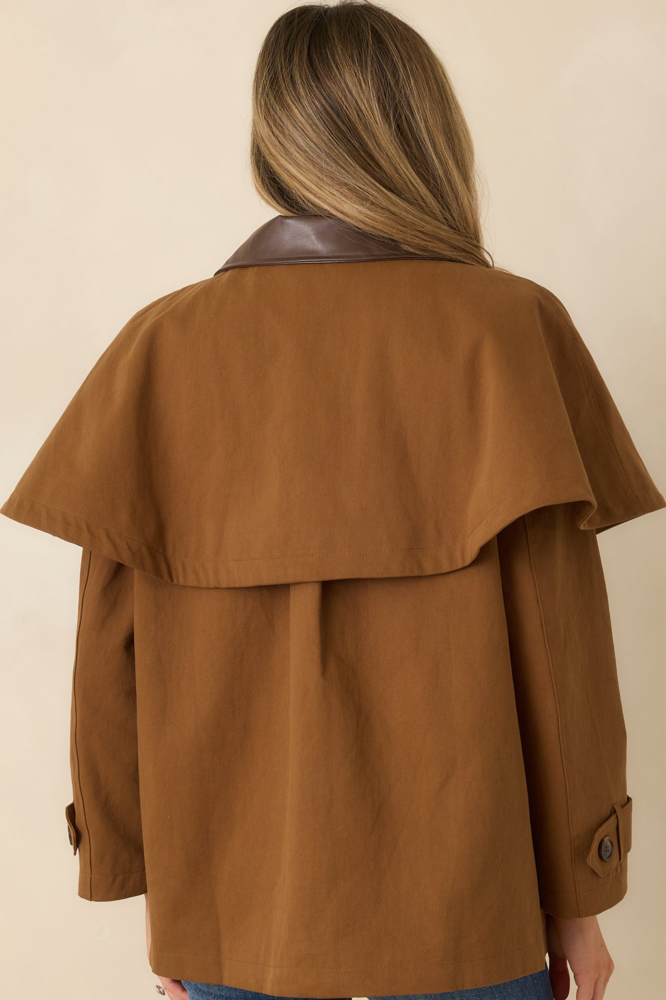 Back view of brown cotton utility jacket featuring cape-style overlay and straight hem for layered shape.