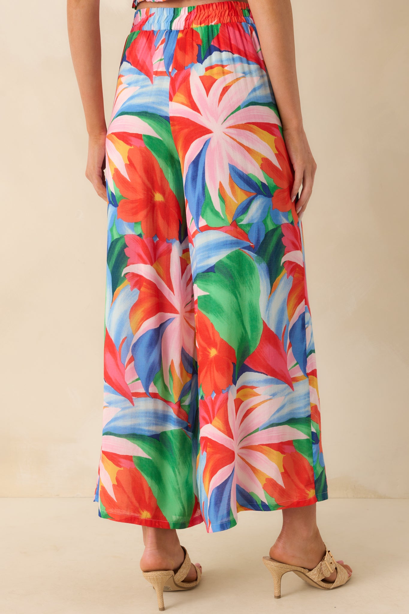 Full back view of the pants displaying the gathered waistband and flow of the tropical floral fabric from waist to hem.