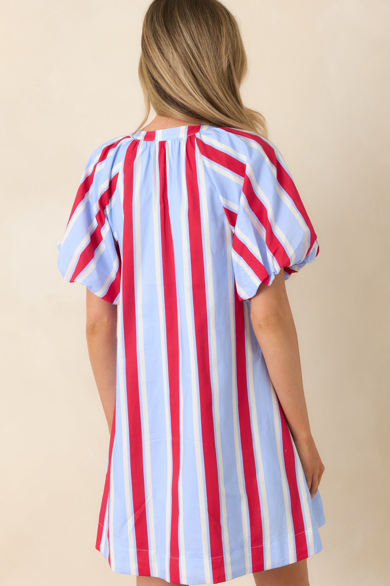 Back view of red and light blue striped cotton mini dress featuring puff sleeves, relaxed fit, and functional pockets