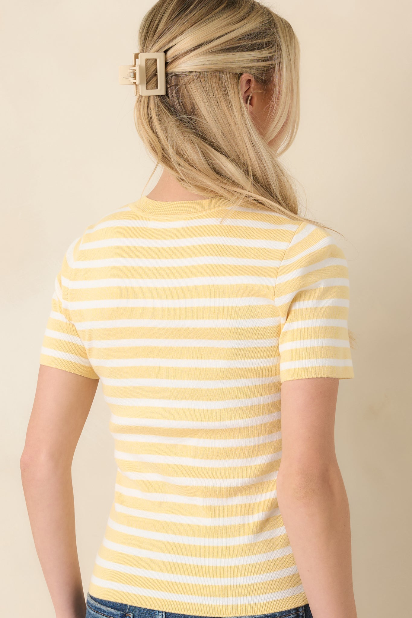 Back view of short sleeve top displaying fitted silhouette and consistent yellow and ivory stripe pattern.