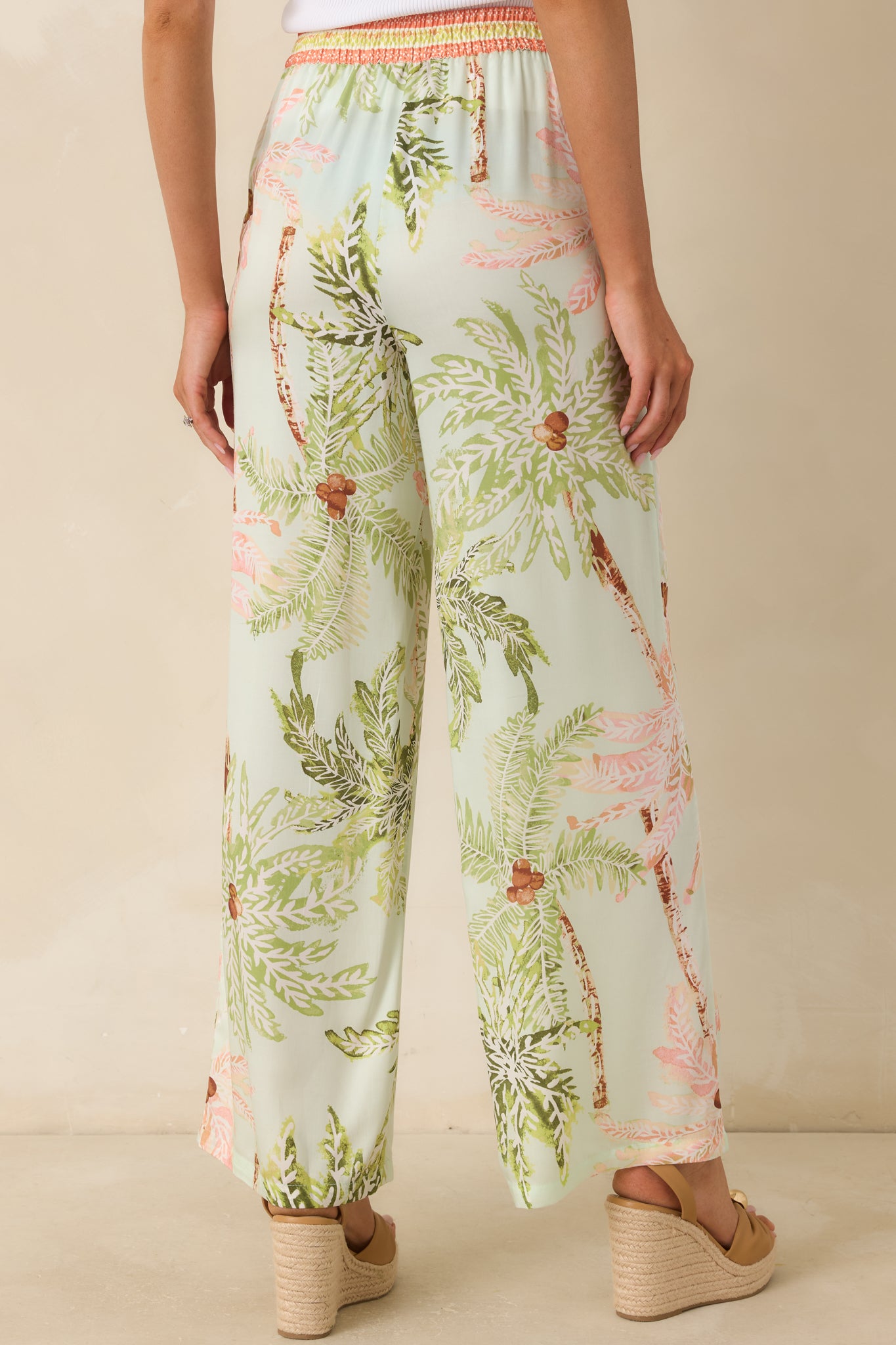 Back view of the mint tropical print pants featuring a relaxed wide-leg fit, elastic waistband, and continuous resort-inspired print.