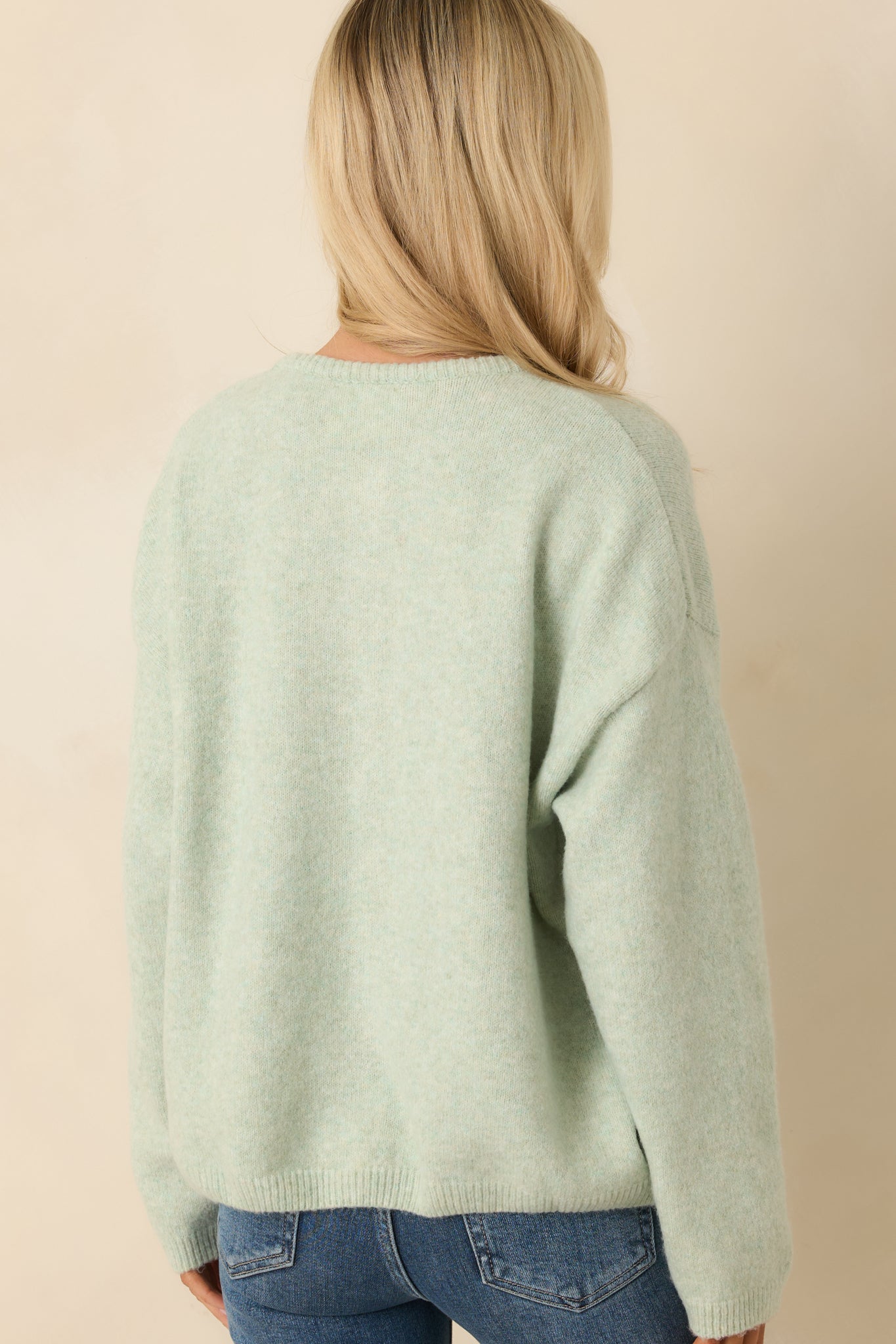 Back view of the mint green cardigan displaying the relaxed silhouette and clean ribbed hem finish.