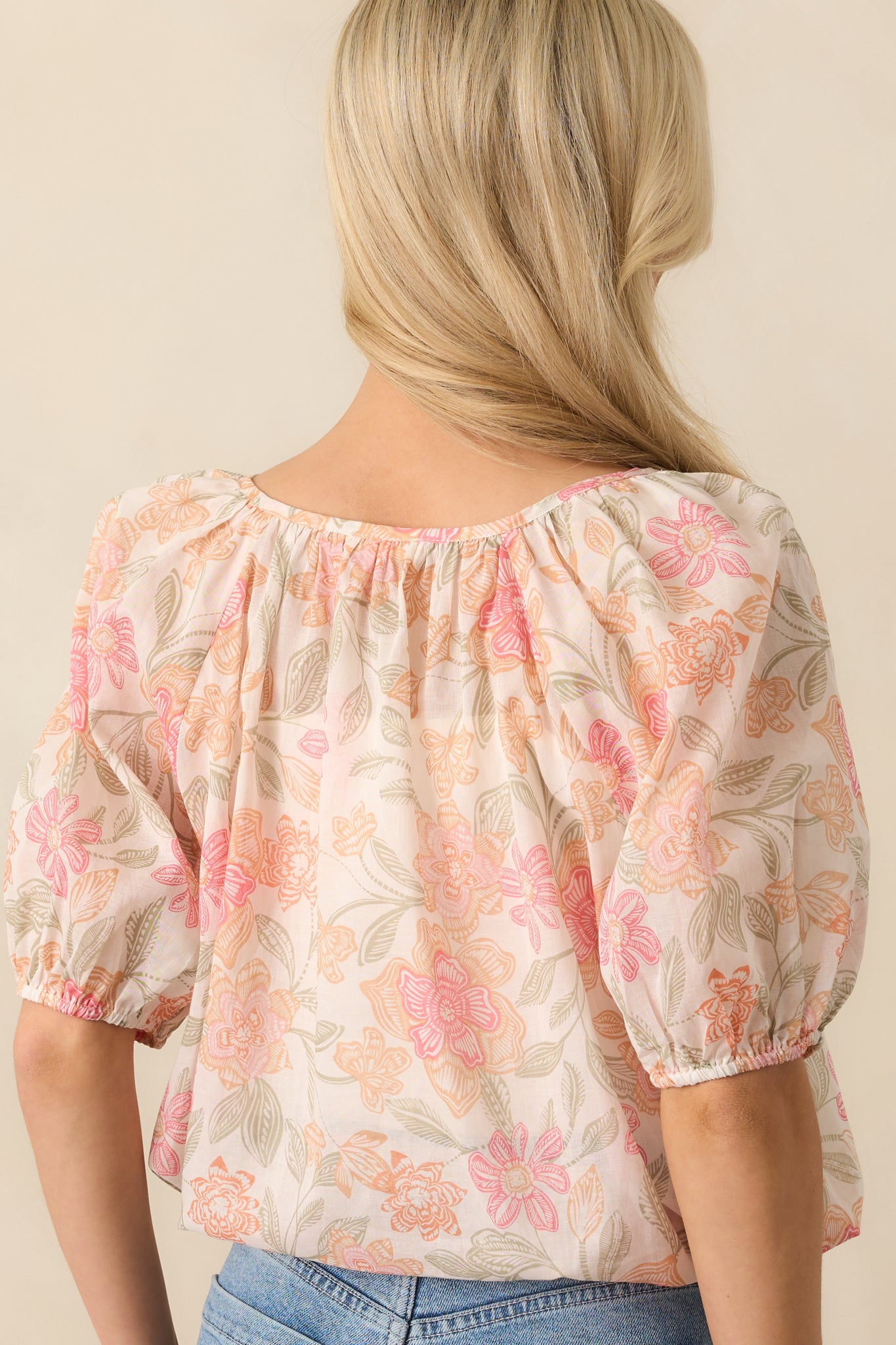Back view of the top displaying the adjustable straps and floral sheer overlay over the ivory lining, with subtle gathering near the drawstring hem.