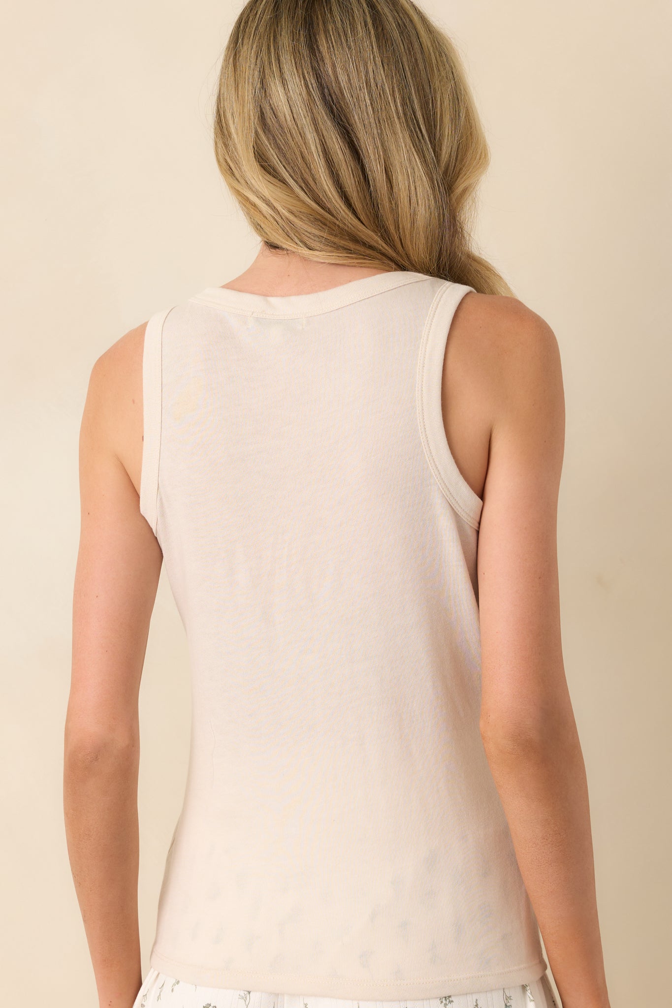Another back view of the light beige sleeveless tank top with a round neckline and smooth fabric finish.