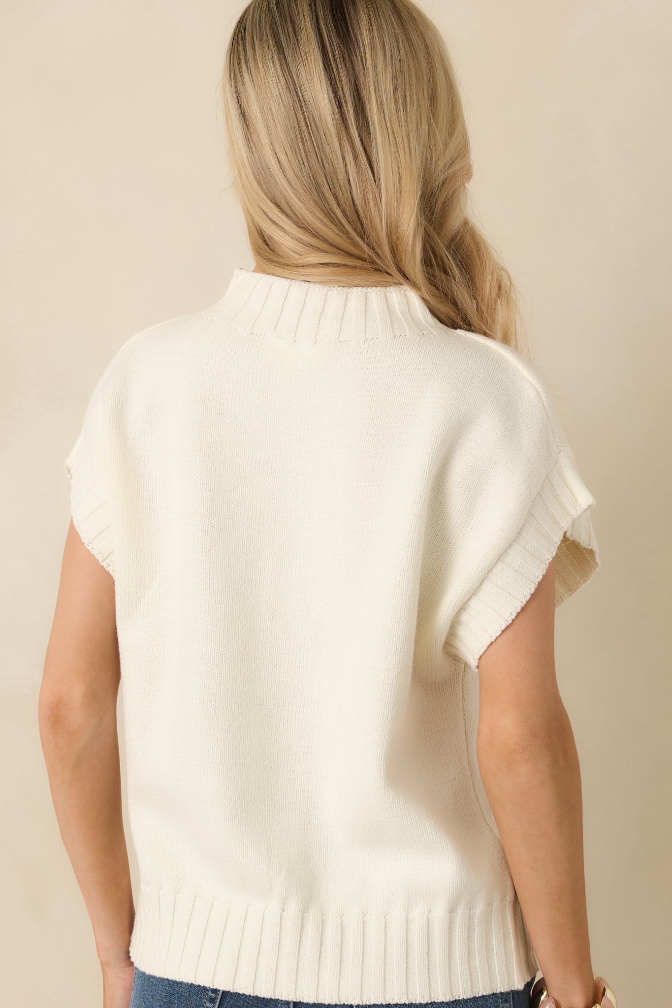 Back view of the ivory sweater showing the relaxed boxy silhouette and ribbed hem.