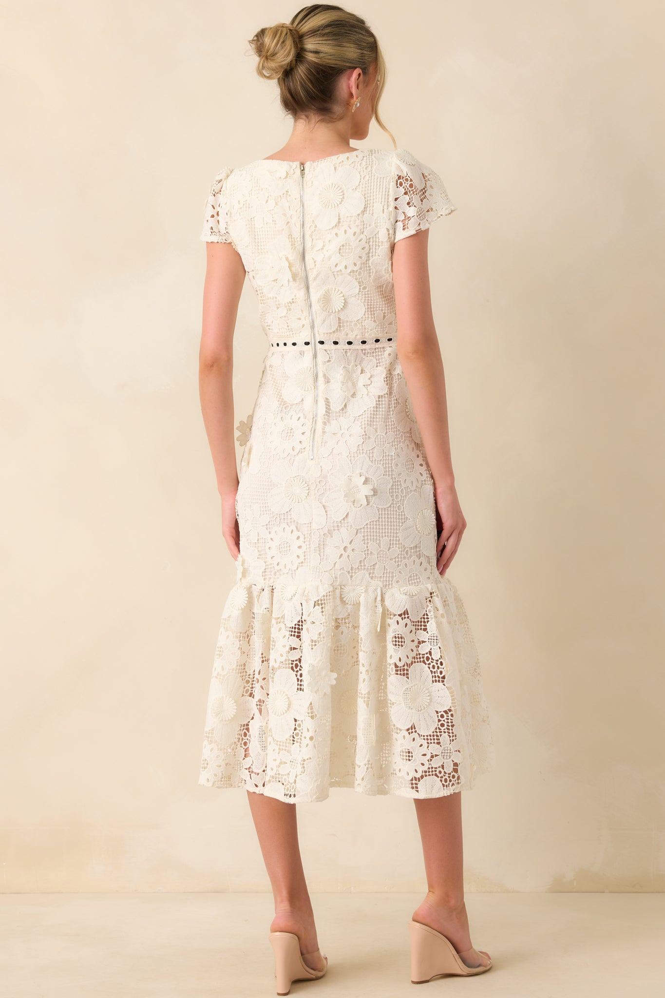 A back view of the dress featuring the zipper closure, fitted waist, and flared mermaid hemline.