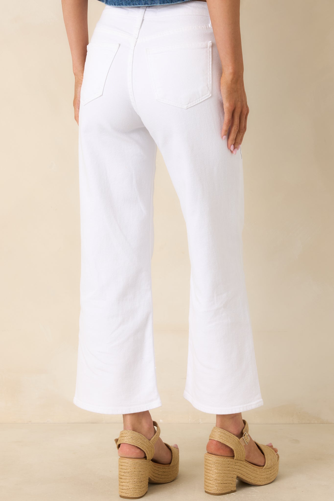 Back view of white cropped wide leg jeans featuring a high-rise fit and classic back pocket styling