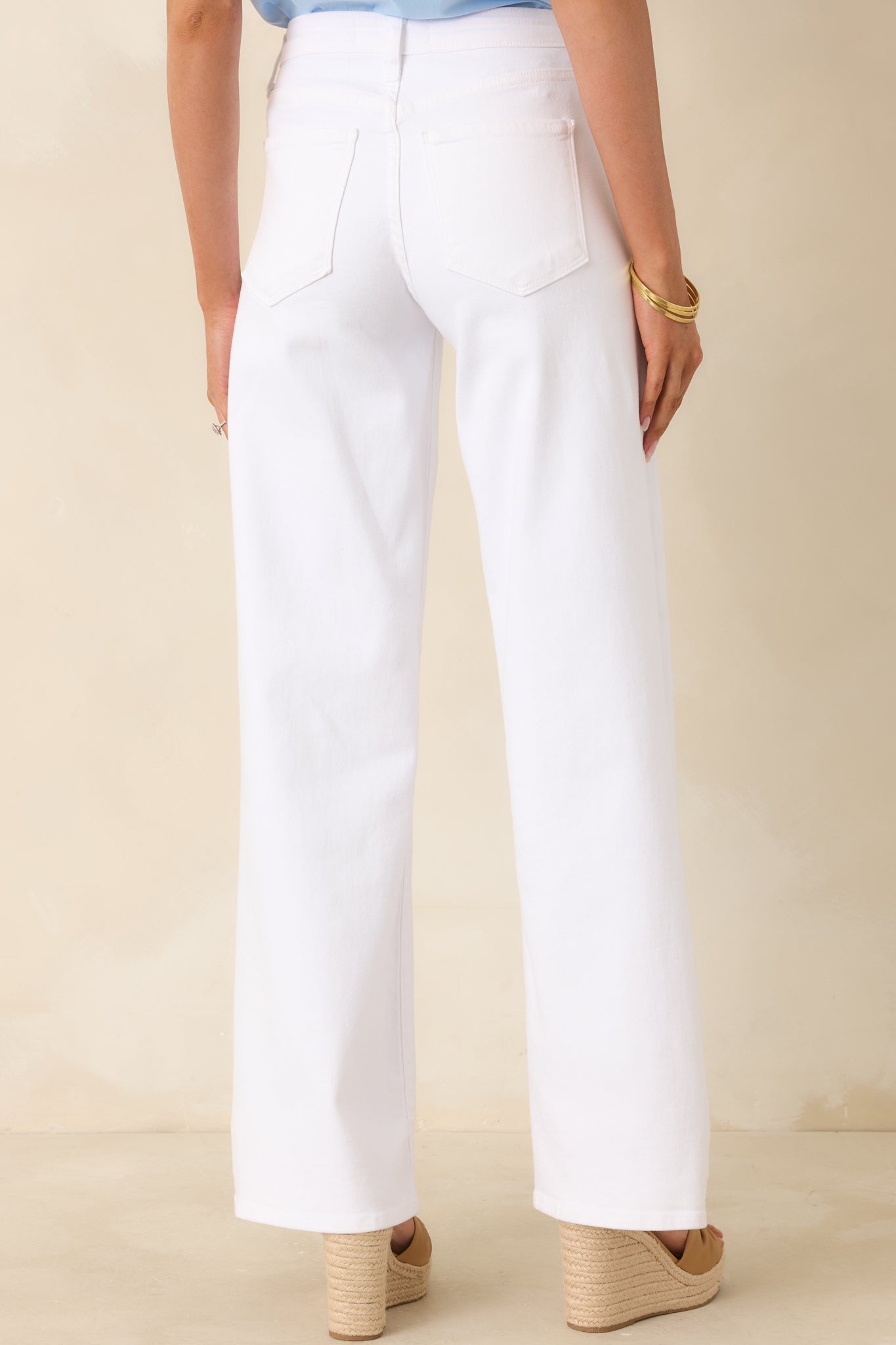 Back view of white high-rise jeans with a wide-leg silhouette, highlighting the clean rear design and flattering fit.