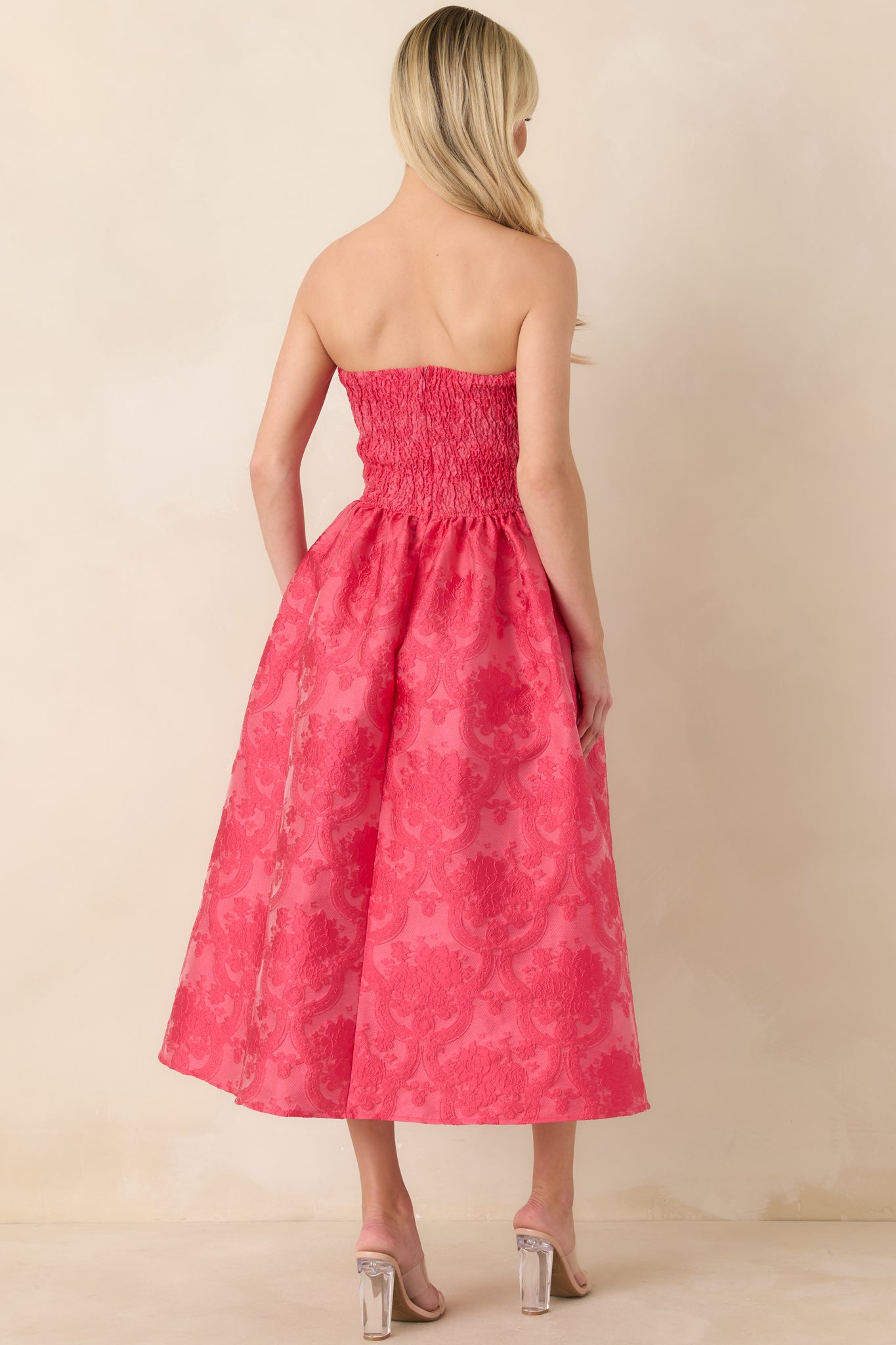 Back view of pink midi dress showing smocked back panel, discrete zipper closure, and softly draped pleated skirt.