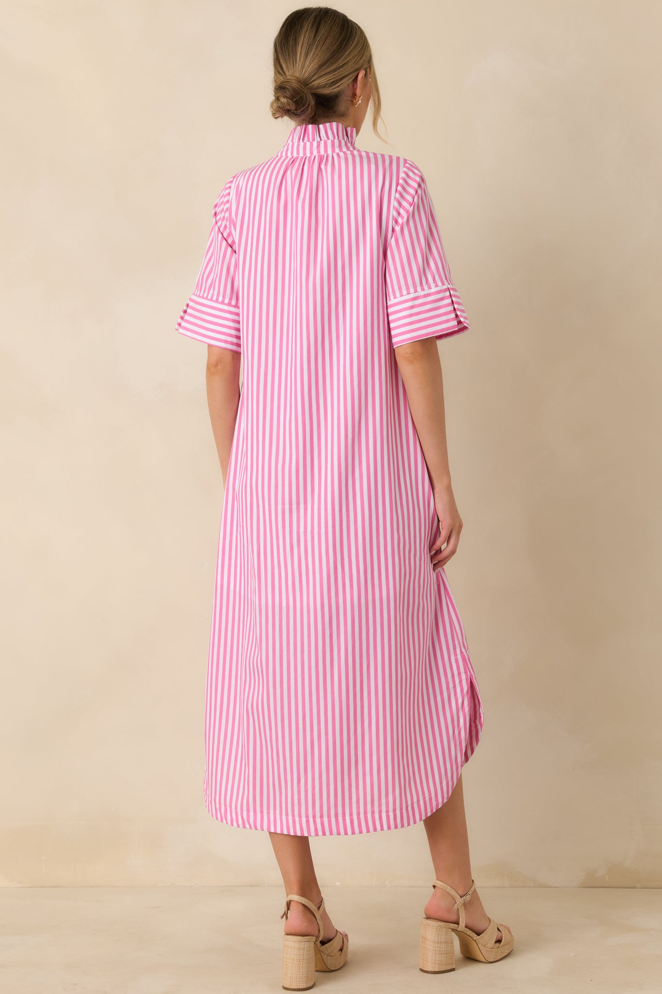Back view of the pink striped shirt dress showing the flowy fit, midi length, and curved shirttail hemline.