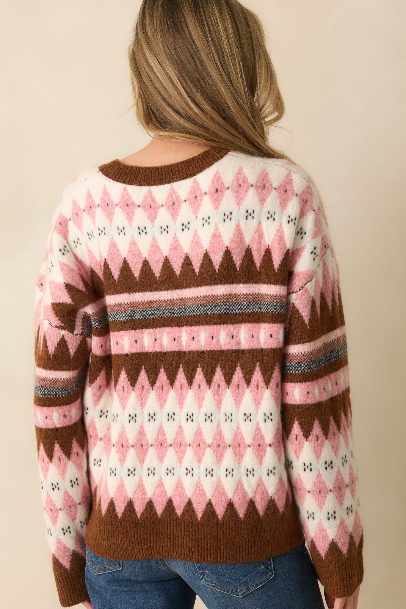 A back view of the pink sweater featuring a relaxed fit and solid knit design with ribbed hem and cuffs.