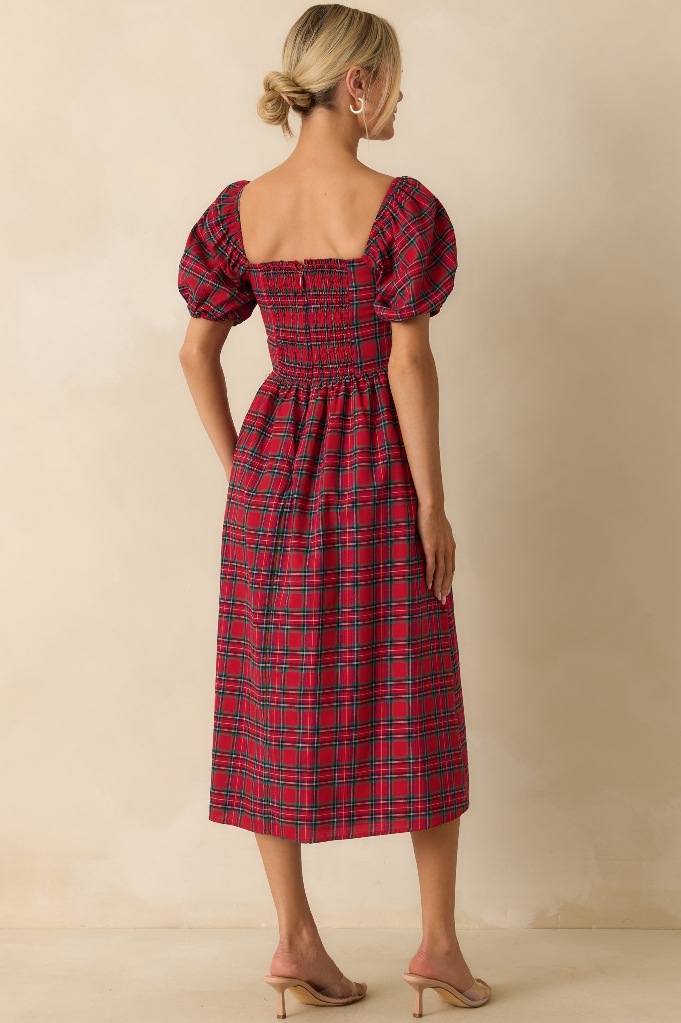 Rear view of red plaid dress displaying smocked back panel, discrete zipper closure, and puff sleeves.
