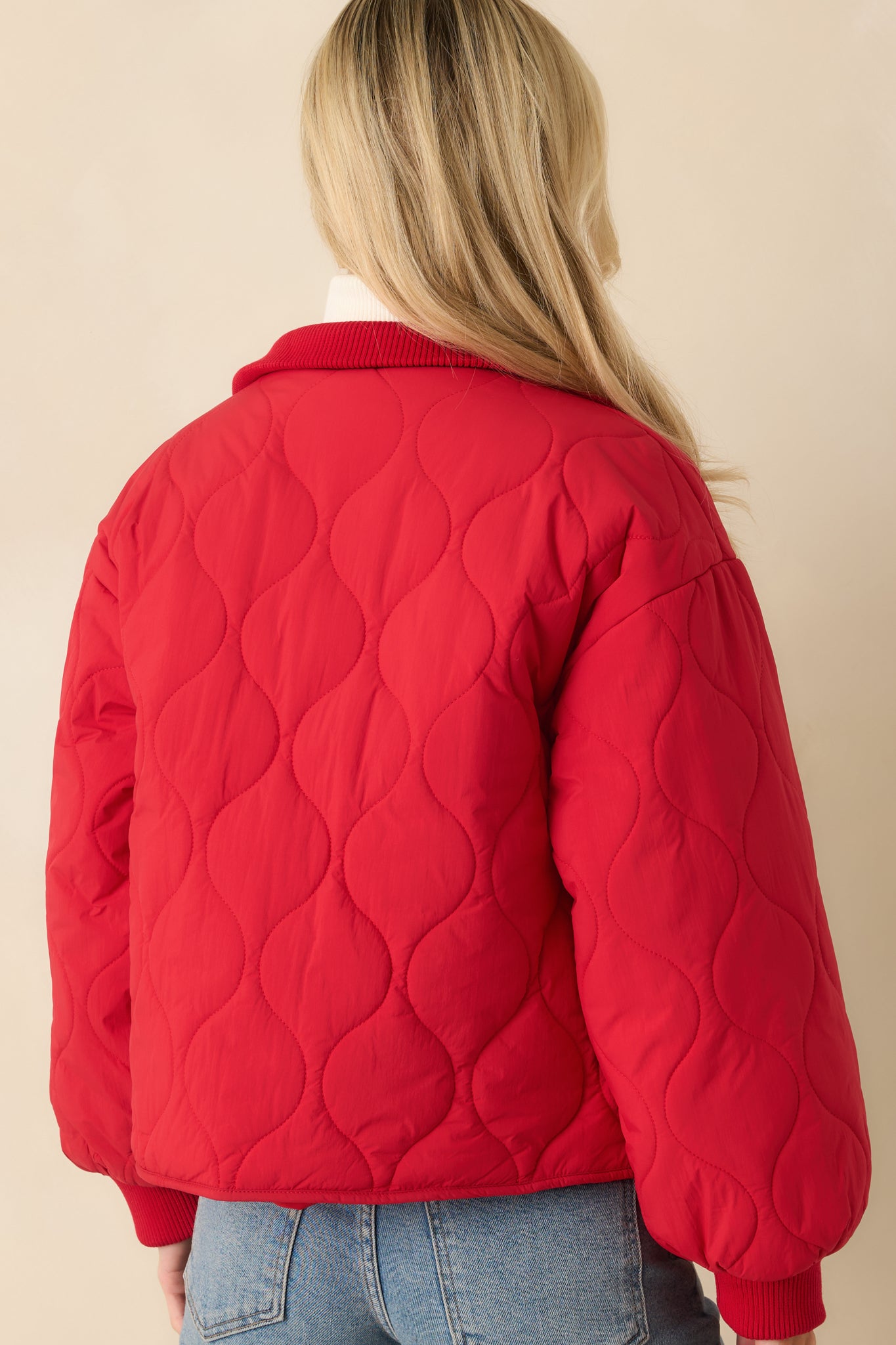 Back view of the red quilted jacket displaying its relaxed fit and consistent padded quilting.