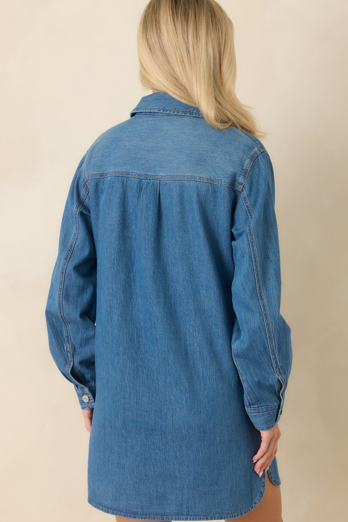 Back view of the relaxed mini dress featuring long sleeves and a subtle high-low hem.