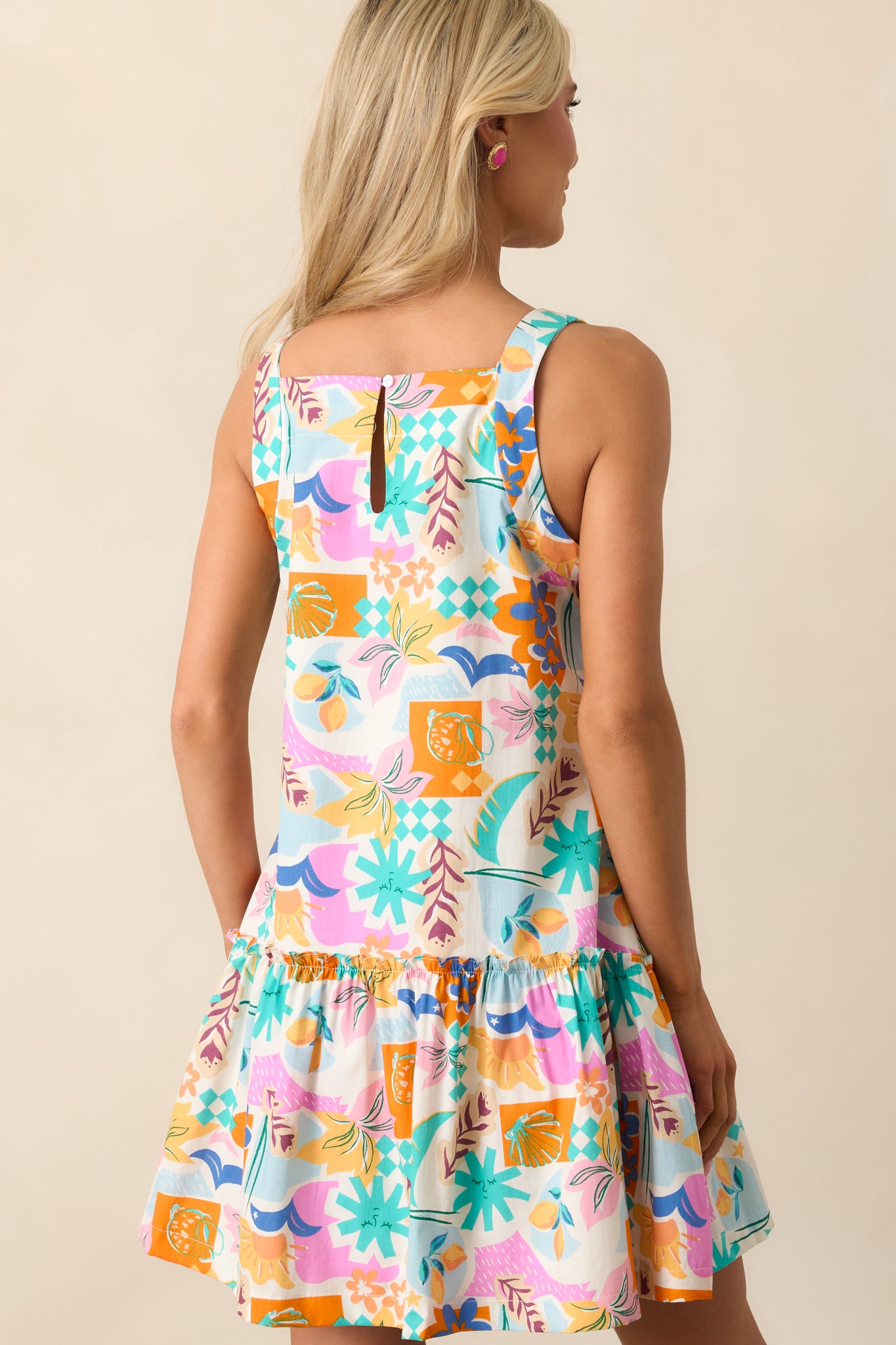 The back view of this pink dress showcases the back keyhole closure, emphasizing the dress’s fun and tropical vibe, with ruffles and functional pockets still visible.