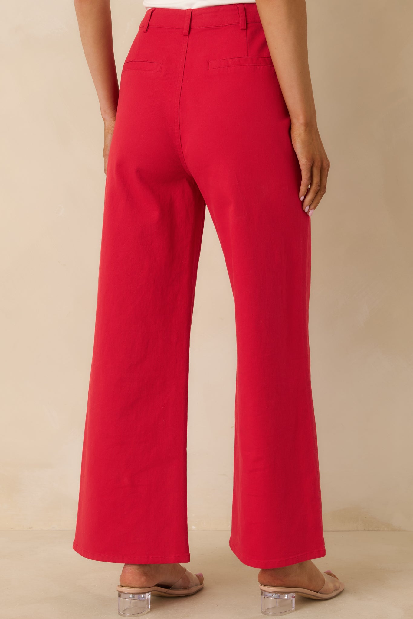 Back view of red wide-leg pants showing non-functional slit pockets and smooth fabric finish.