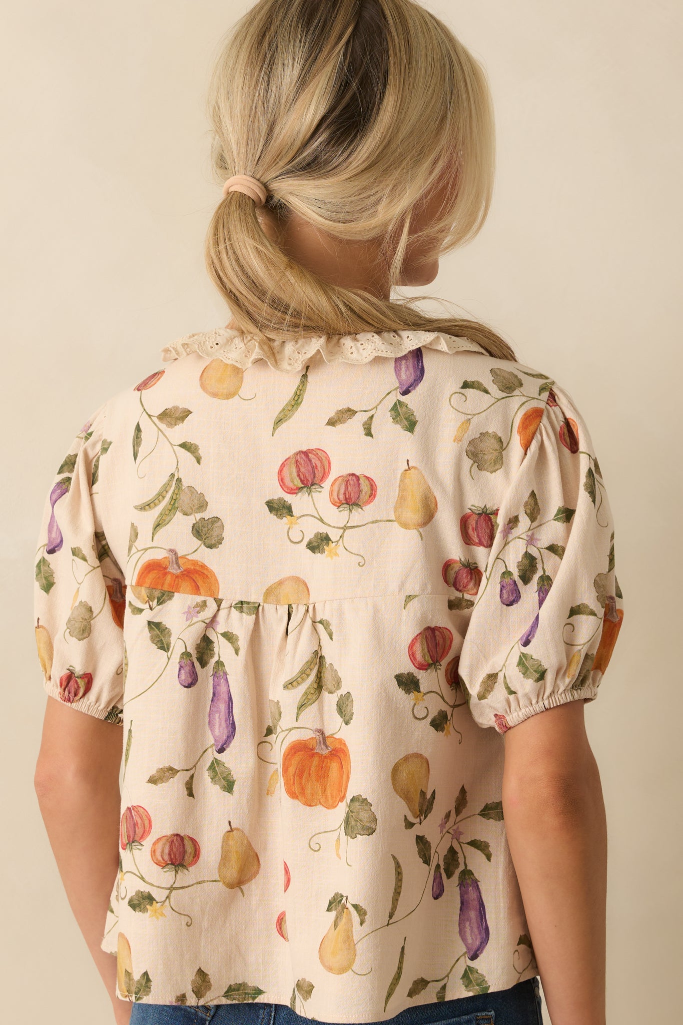 Back view of ivory blouse with relaxed cropped fit and puff sleeves finished with elastic cuffs.