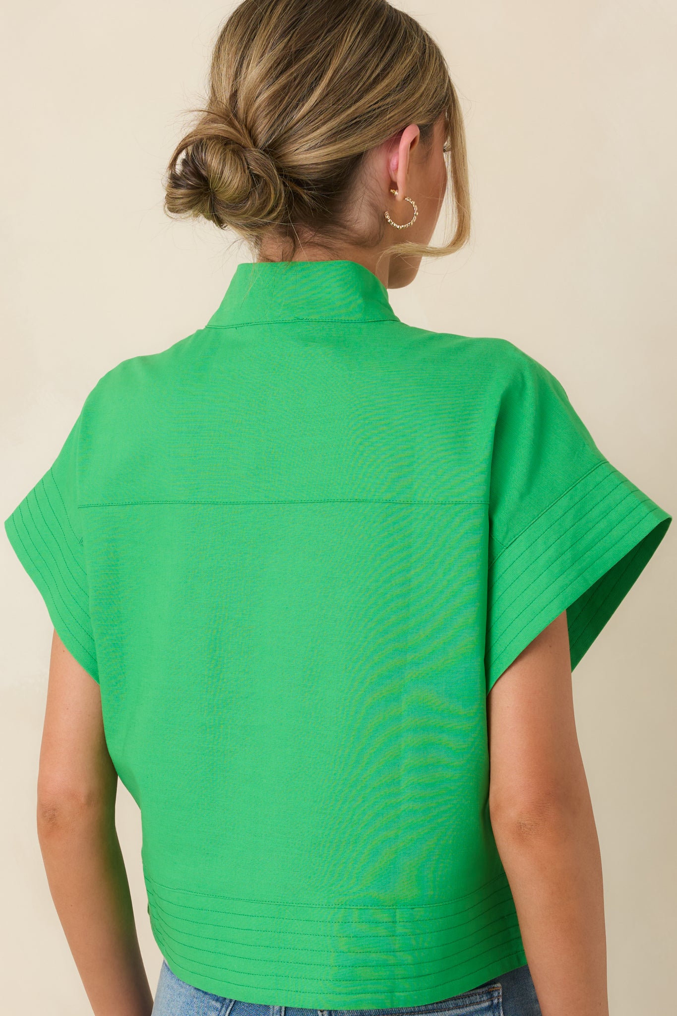 Back view of the green boxy top showing smooth back panel, short sleeves, and straight hemline.