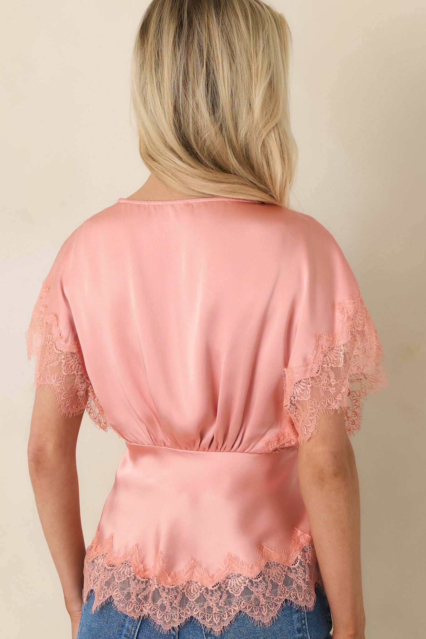 Back view of blush pink blouse showing smooth satin-like fabric, relaxed fit, and clean pull-on design.