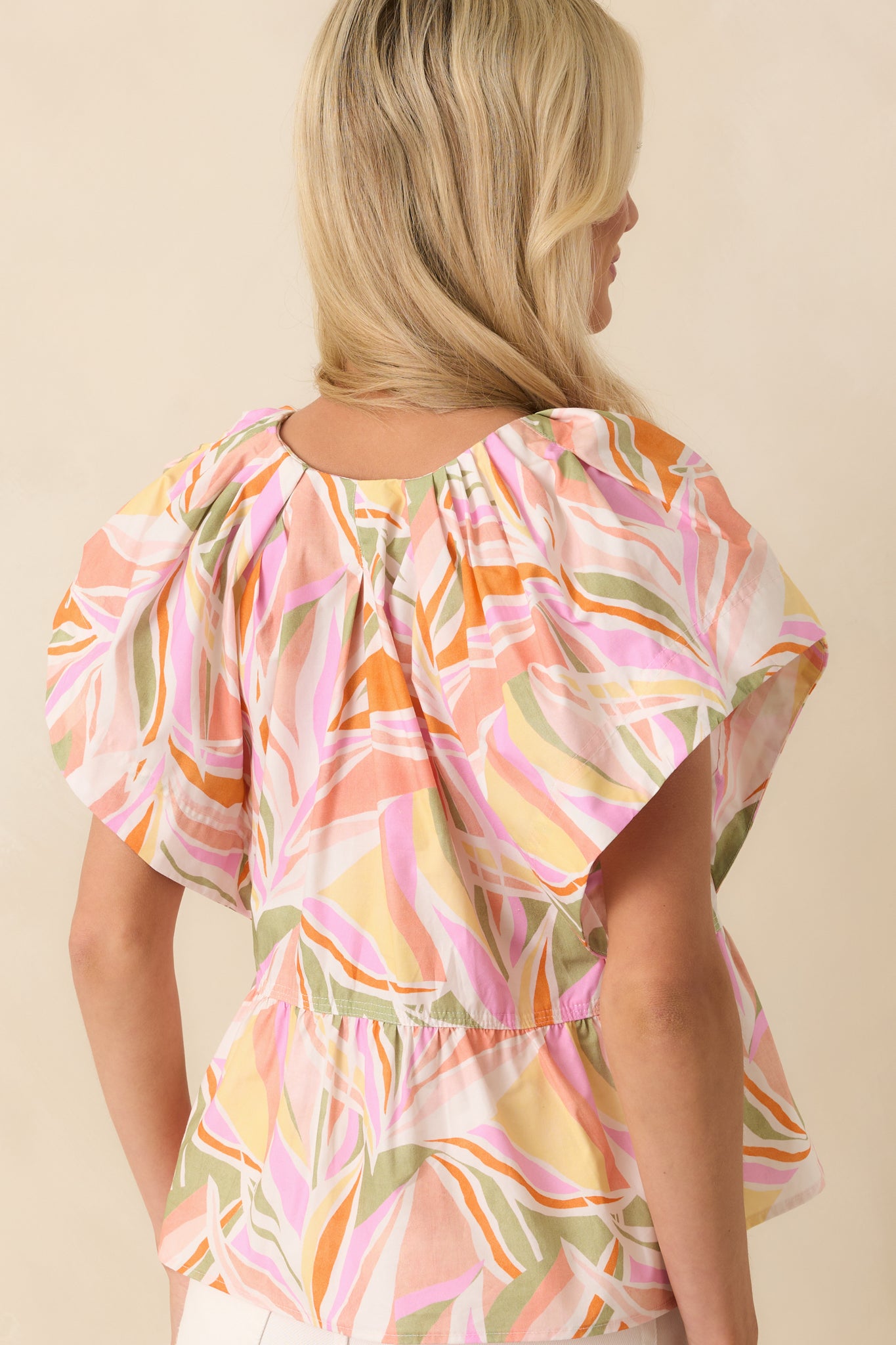 Back view of the top showing the continuation of the abstract floral print and the peplum silhouette from behind.