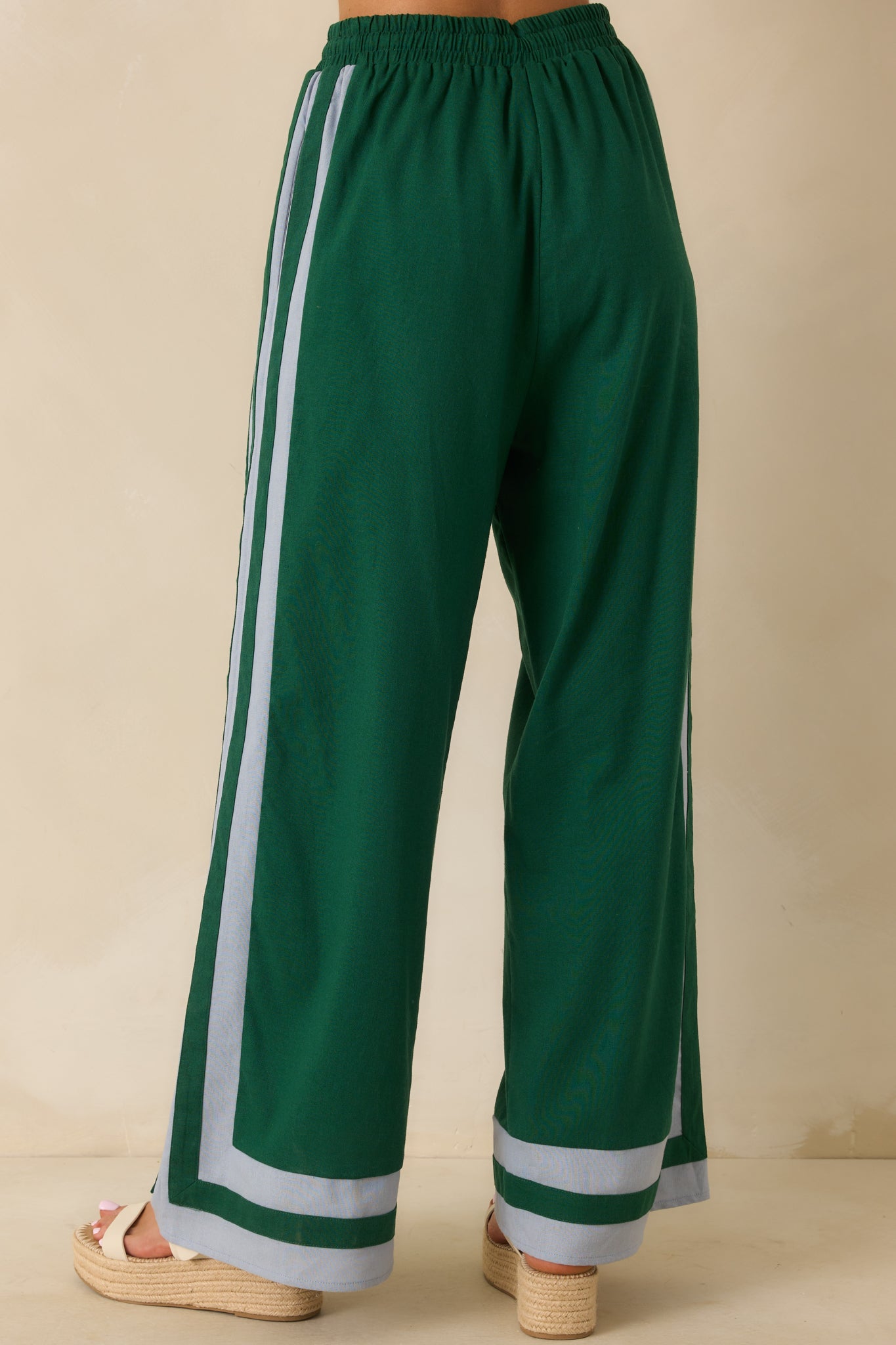 Back view of the green pants showing the elastic waistband, light blue trim, and wide-leg silhouette.