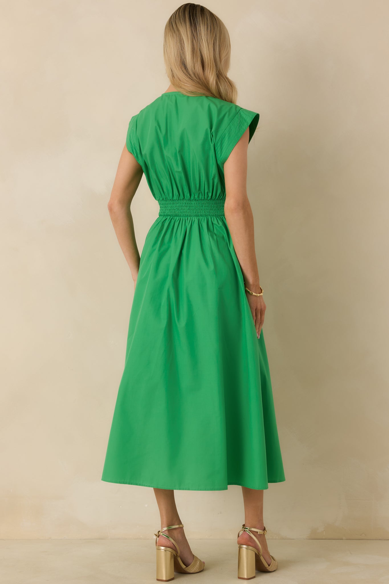 Back view of green sleeveless midi dress showing the fitted waist and flowing gathered skirt.