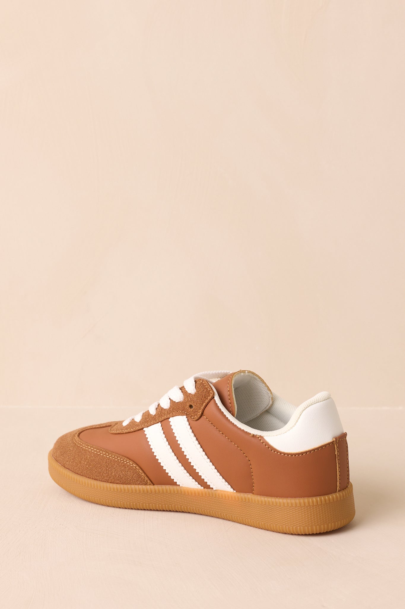 A back view of the sneakers, showing the padded collar, caramel brown upper, and gum outsole at the heel.