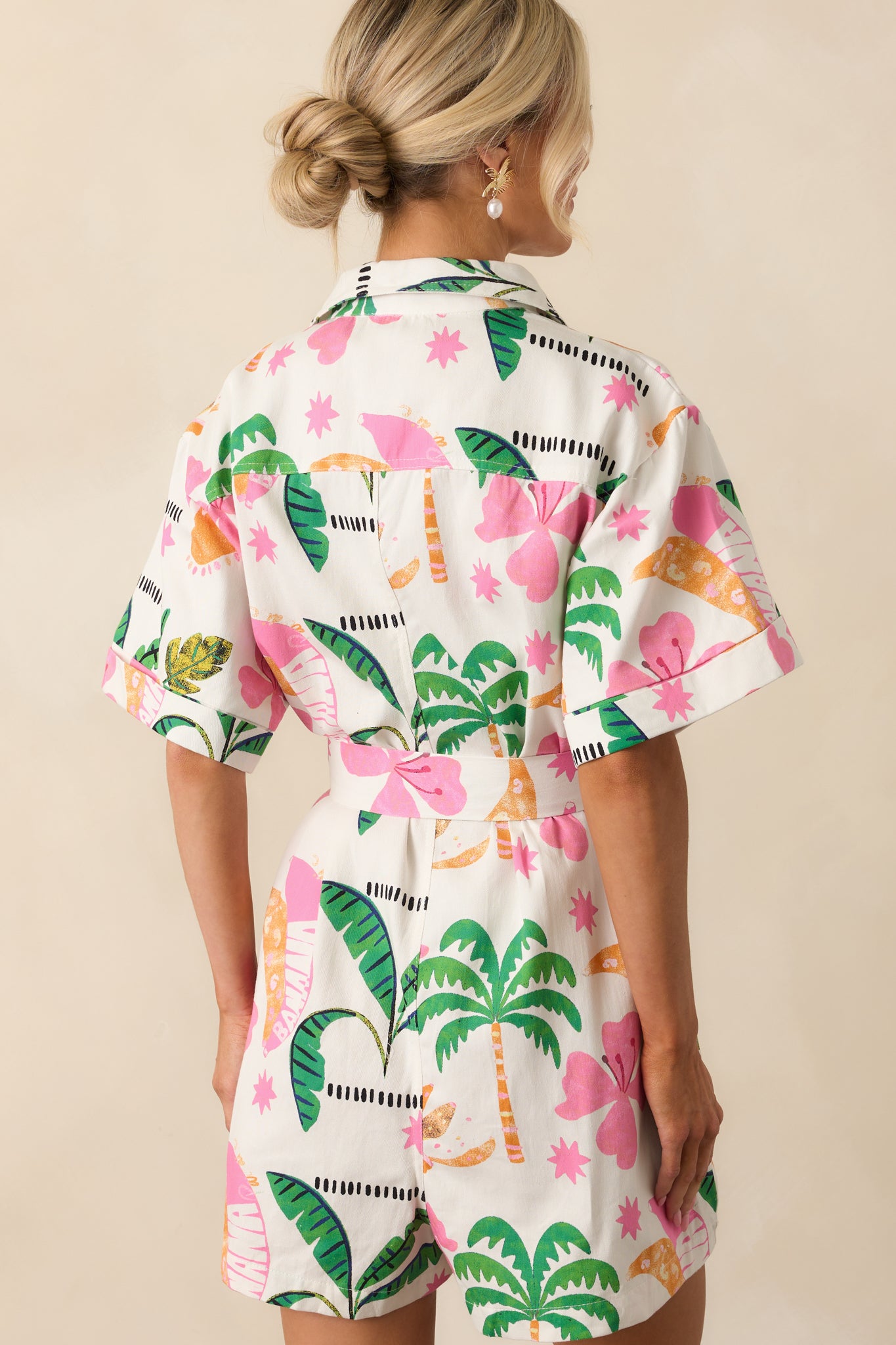 Back view of the romper showing the continuation of the tropical print, short sleeves, and relaxed fit across the shoulders and waist.
