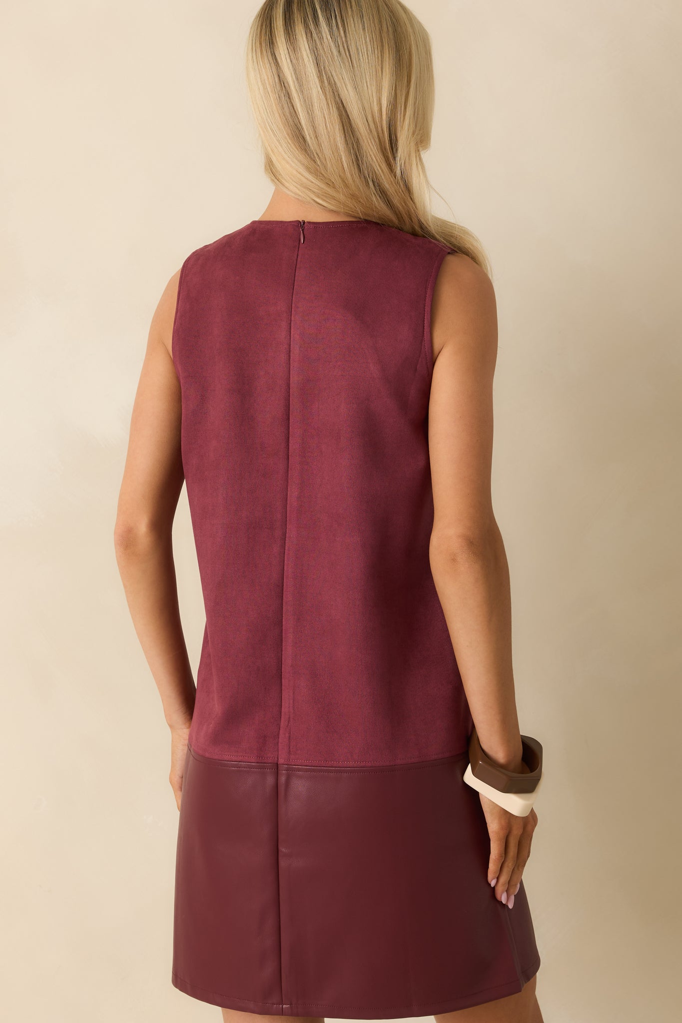Back view of sleeveless wine red mini dress featuring a back zipper closure and mixed-media shift silhouette.