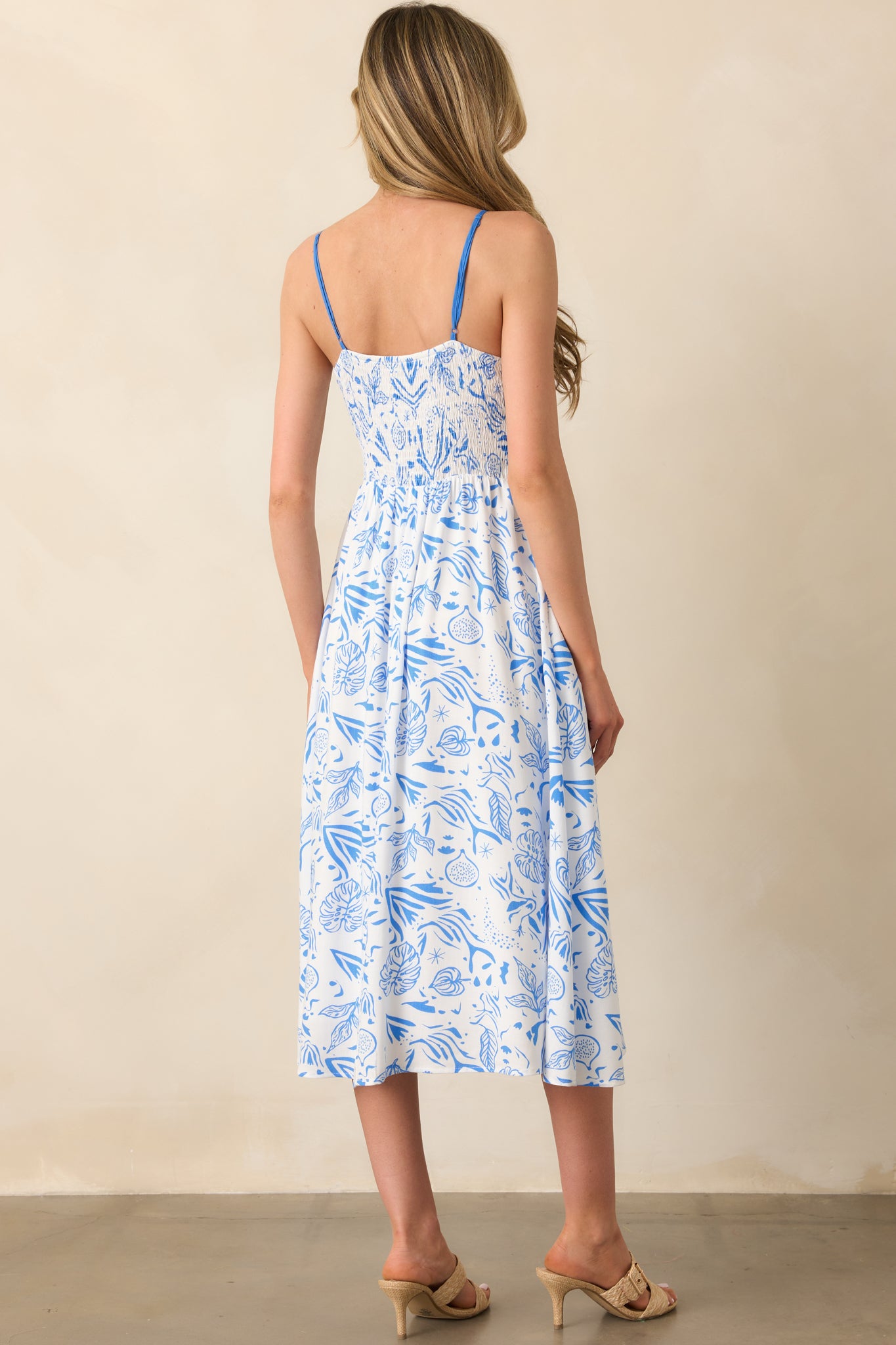 A view from behind showing the smocked back panel, adjustable straps, and consistent tropical print across the dress.