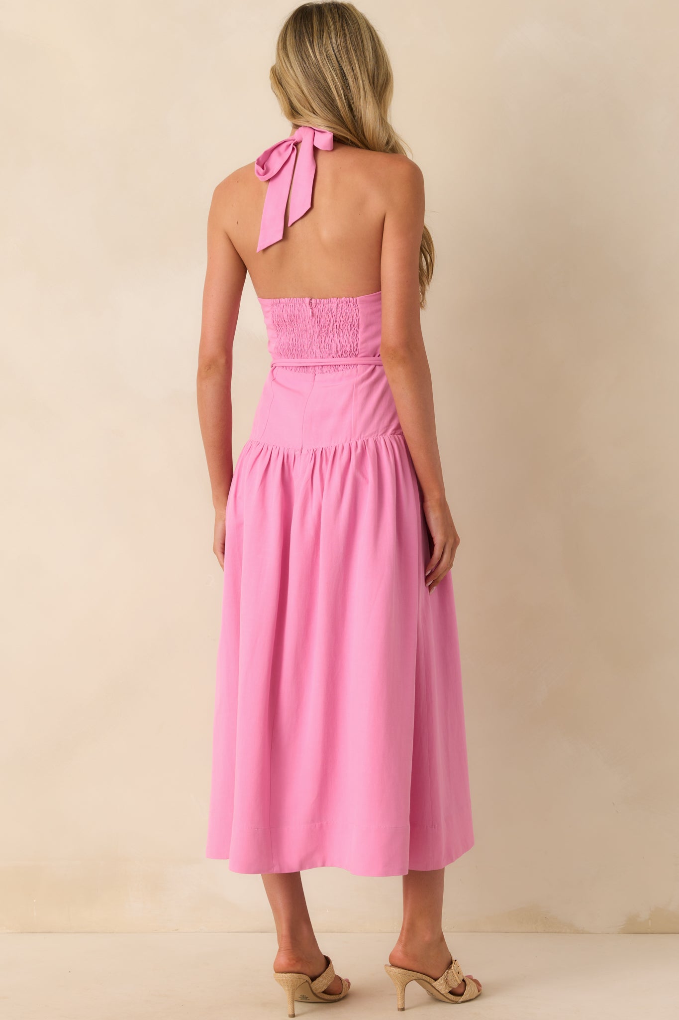 A back view displaying the smocked back panel and hidden back zipper closure beneath the halter neckline ties.