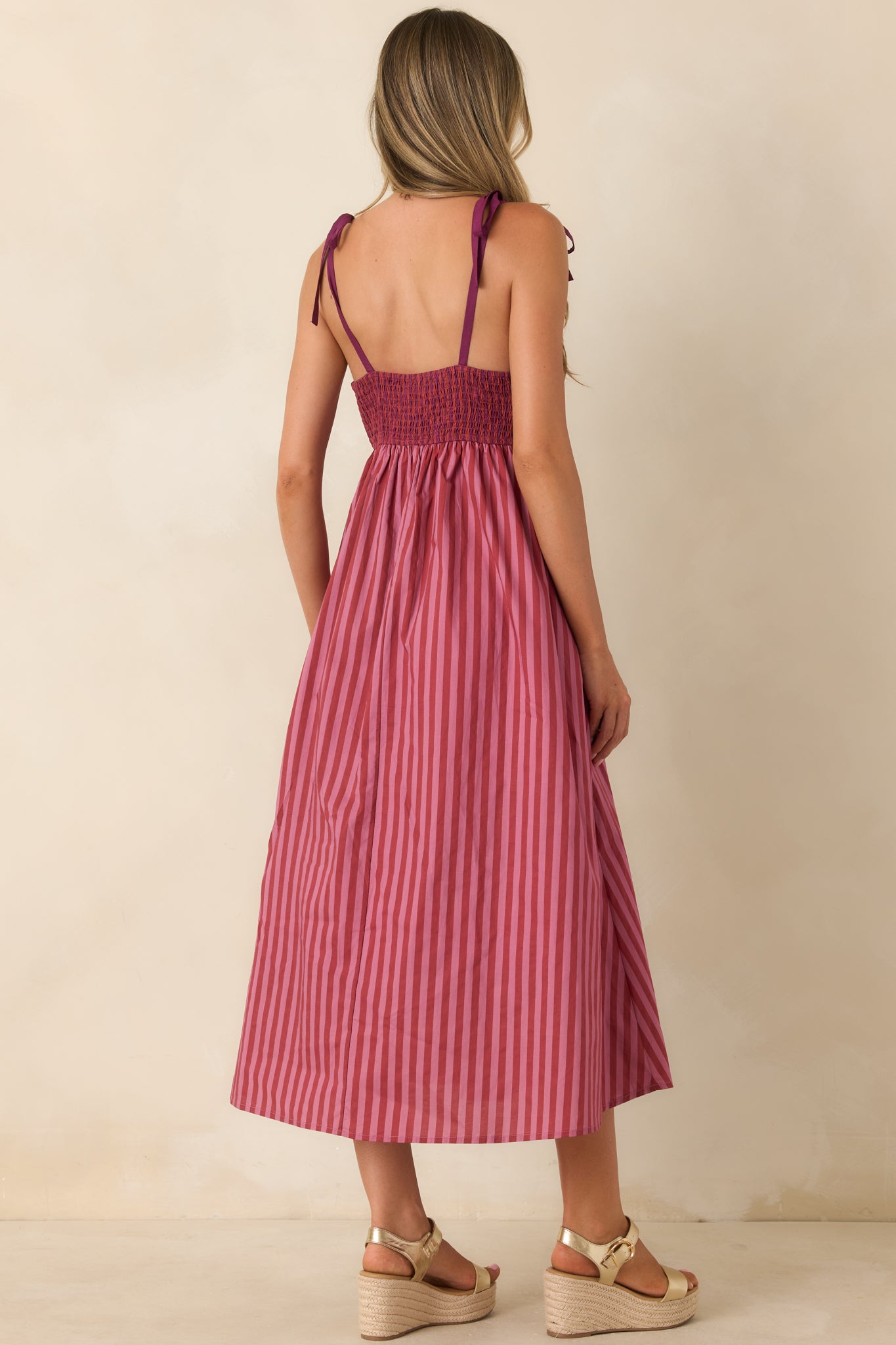 Back view of the striped midi dress featuring a smocked back and adjustable tie straps.