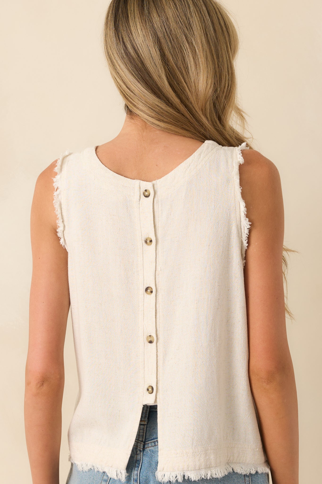 Back view of the tank top featuring a row of functional buttons and a frayed hemline at the bottom edge.
