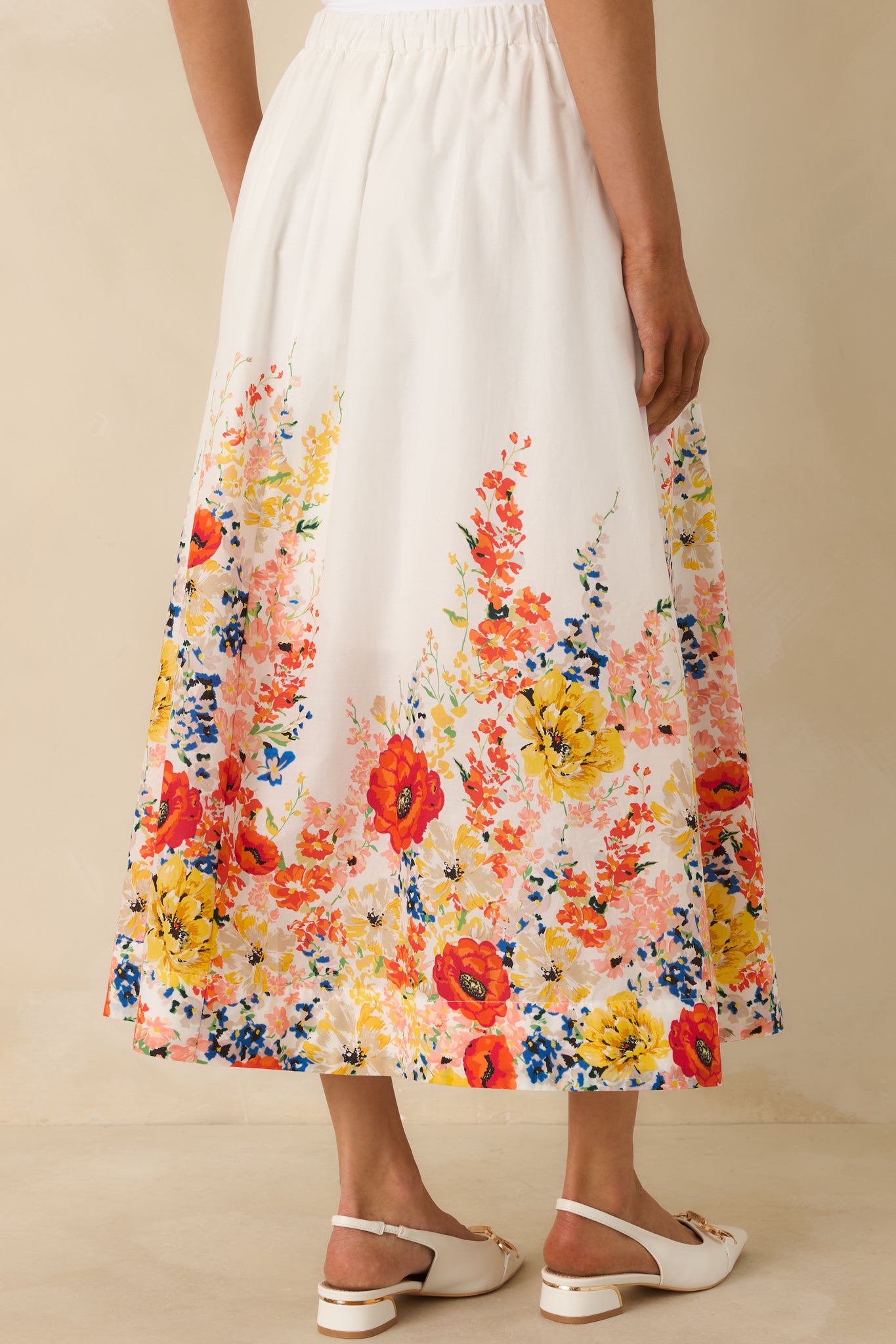 Back view of the white cotton maxi skirt showing the flowy silhouette, elastic waistband, and continuous floral hem print.
