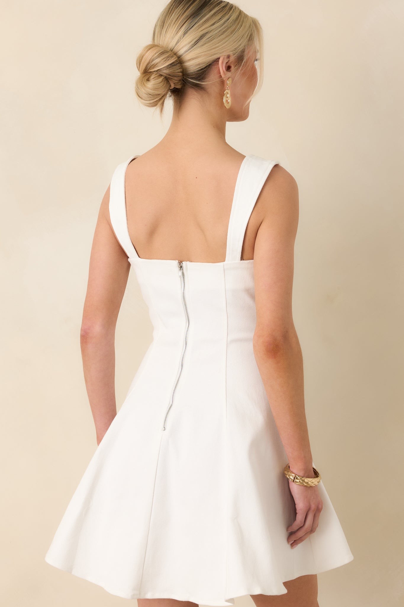 Back view of the white mini dress displaying the silver hardware zipper and sleeveless design.