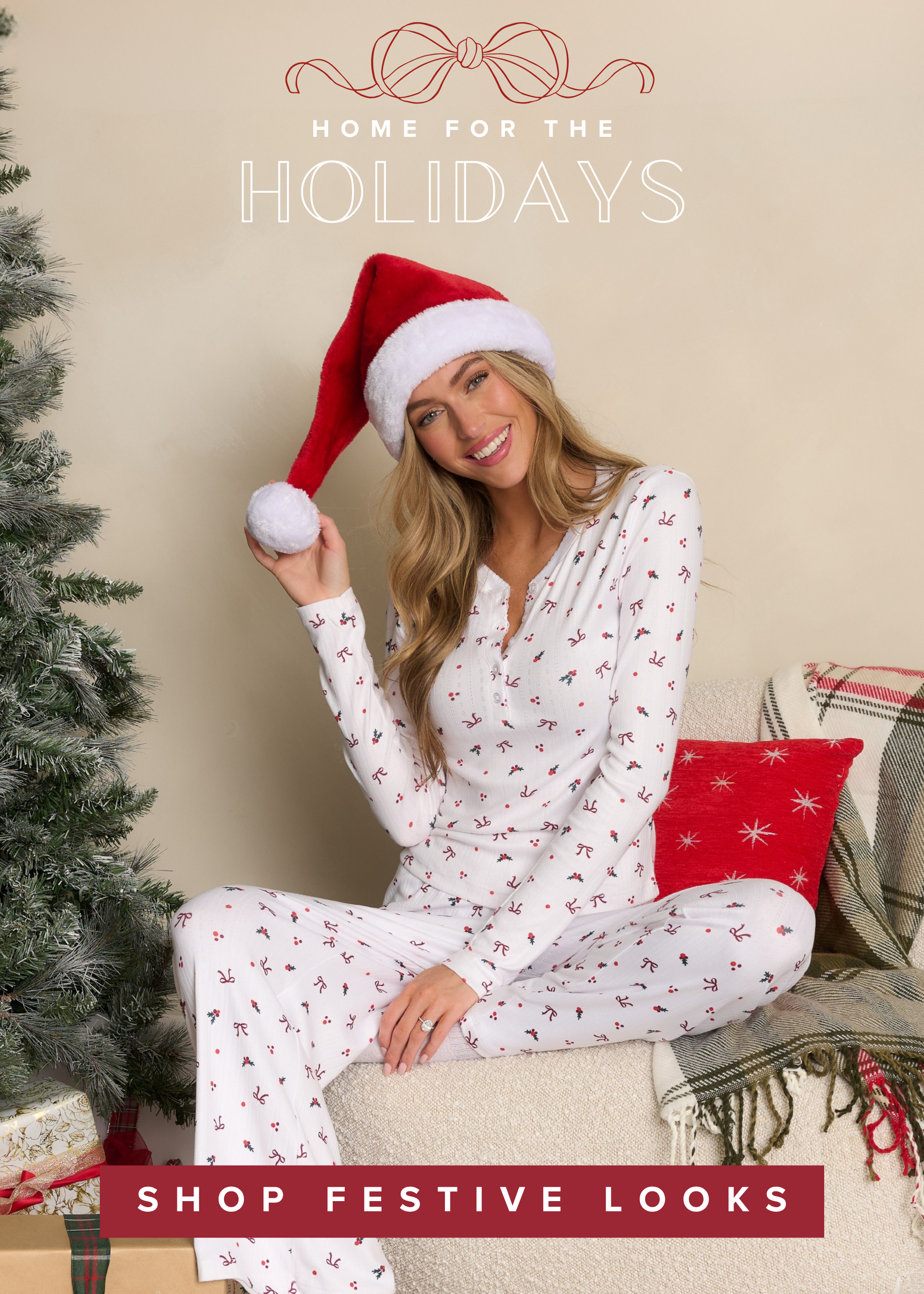 Model in white candy cane pajamas by a Christmas tree. Shop cozy women’s holiday loungewear.