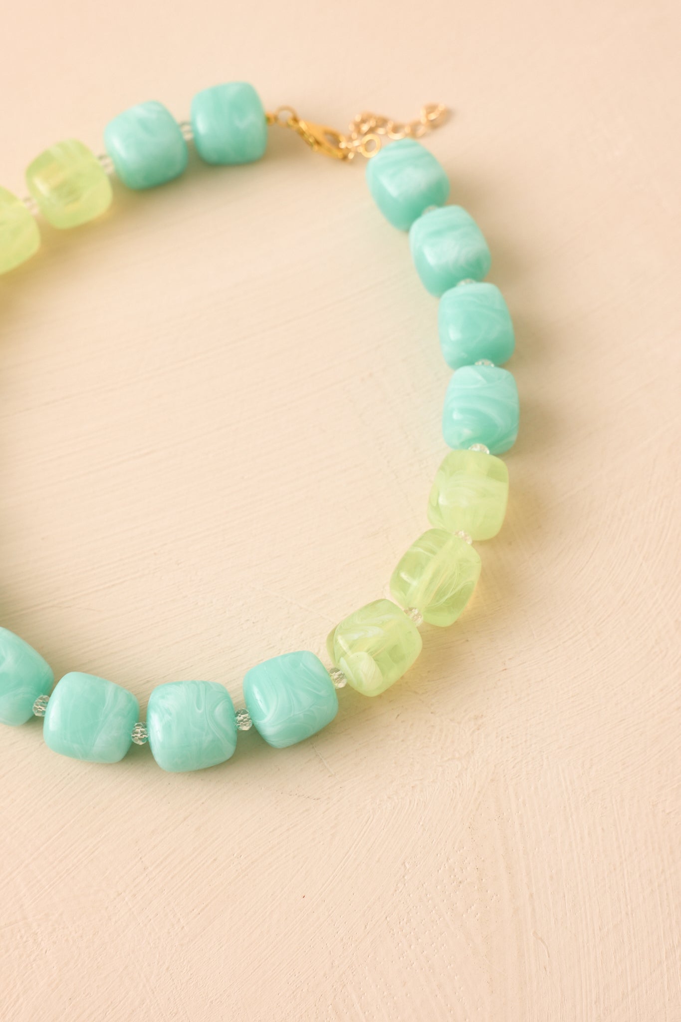 Close-up of the necklace showcasing the smooth marbled aqua and light green beads, clear spacer accents, and polished detailing.
