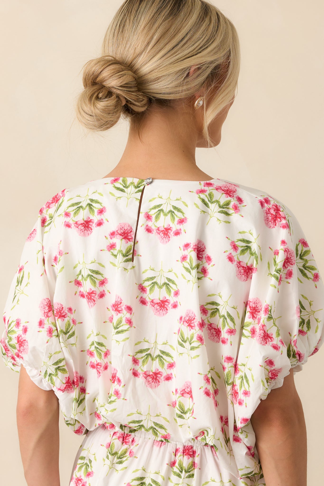 A view from behind of the floral print top, displaying the keyhole closure and continuation of the elastic bubble hem.