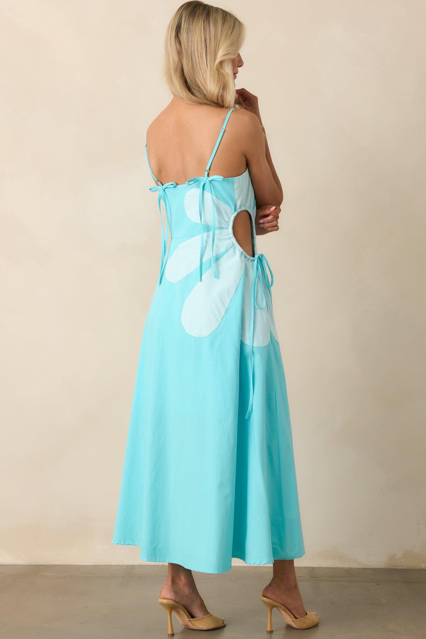 A view from behind featuring decorative bow accents, adjustable straps, and hidden zipper on the maxi dress.