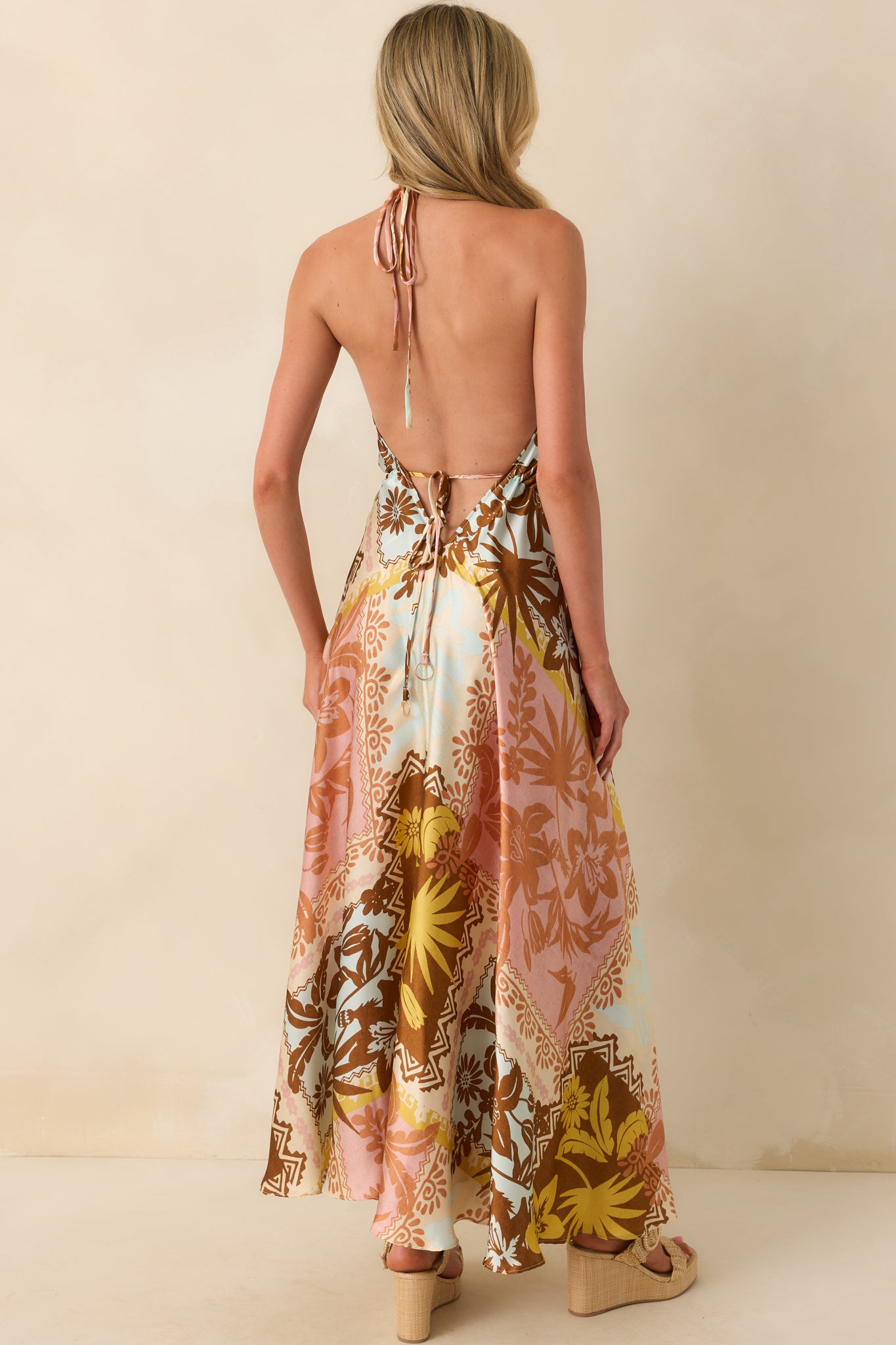 A view from behind displaying the open back design, self-tie waist closure, and flowing skirt of the maxi dress.
