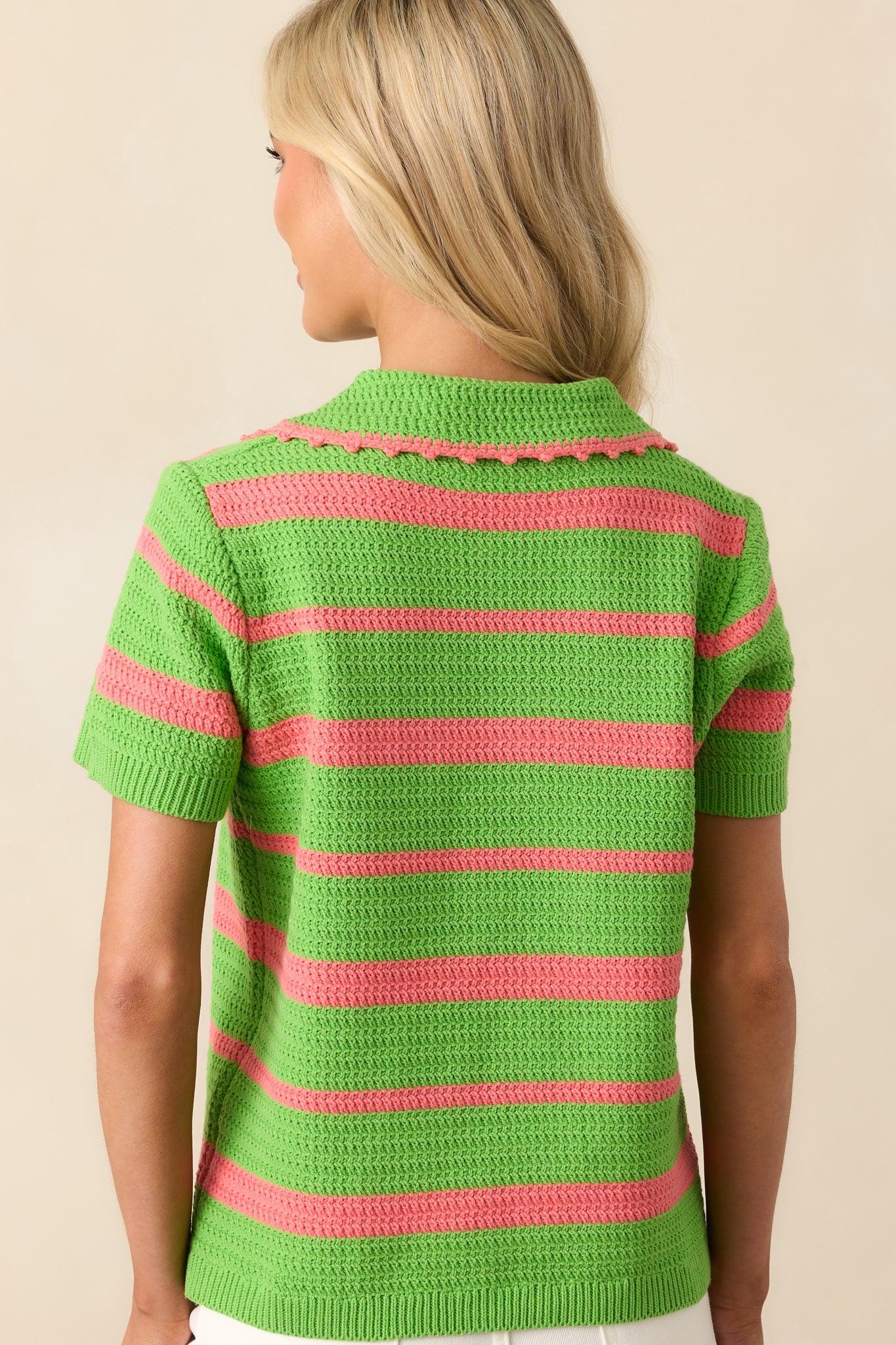 View from behind of the striped knit top, showing the continuation of the green and pink pattern and short sleeves.