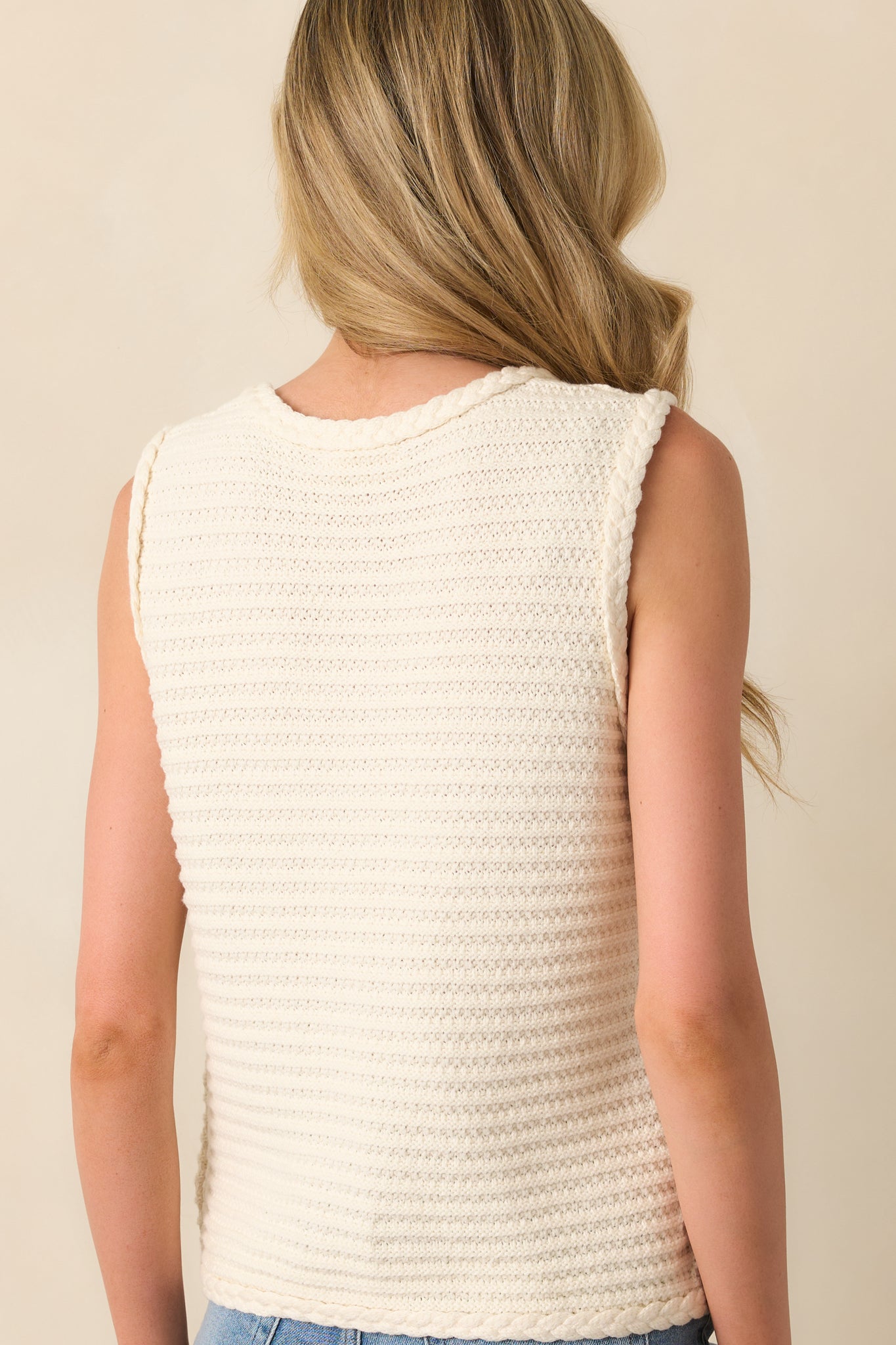 A view from behind of the ivory sweater vest, displaying the smooth knit fabric and relaxed fit.
