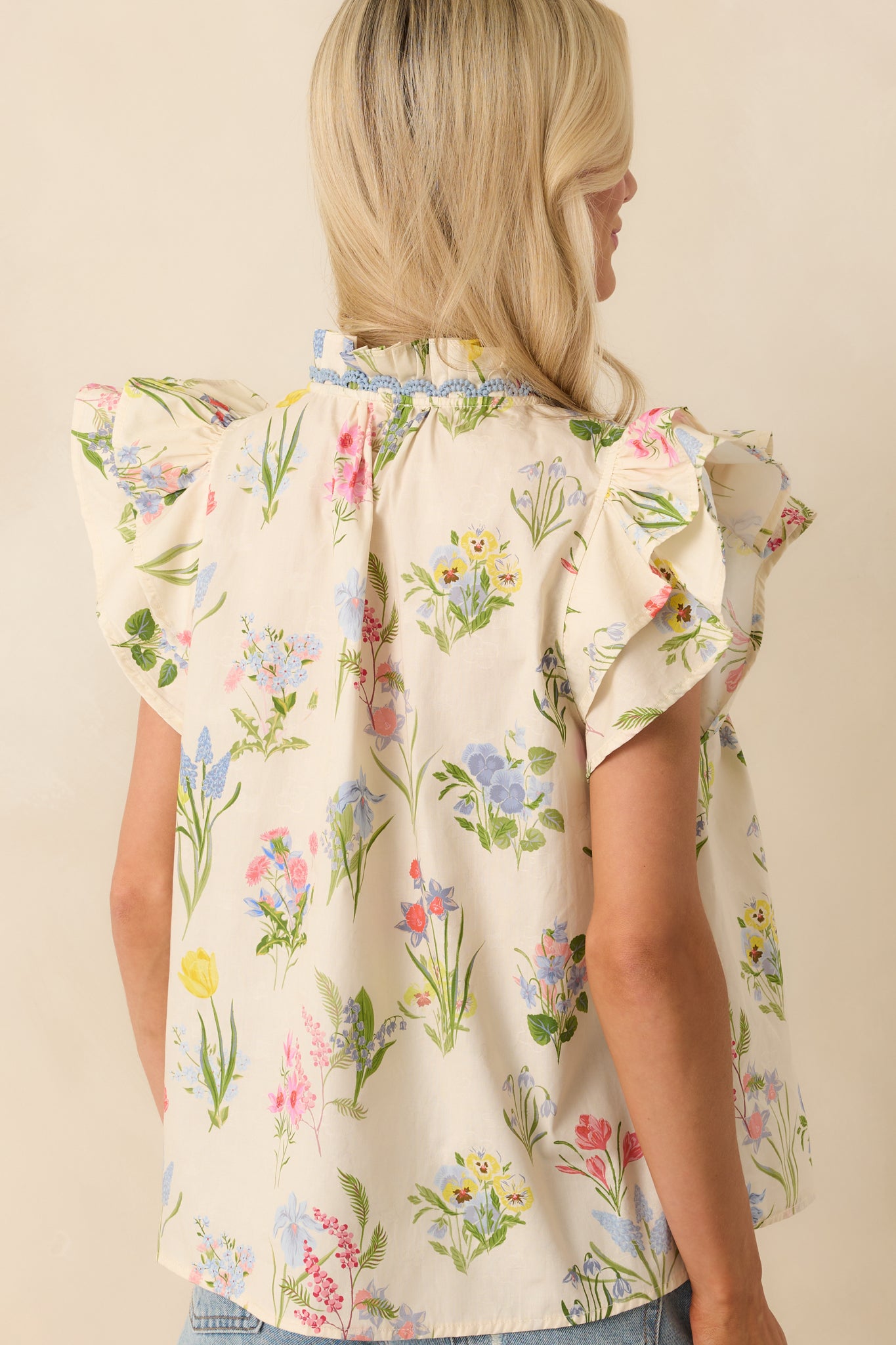 A view from behind showing the relaxed fit and shoulder construction of the ivory top with continued floral motif coverage.
