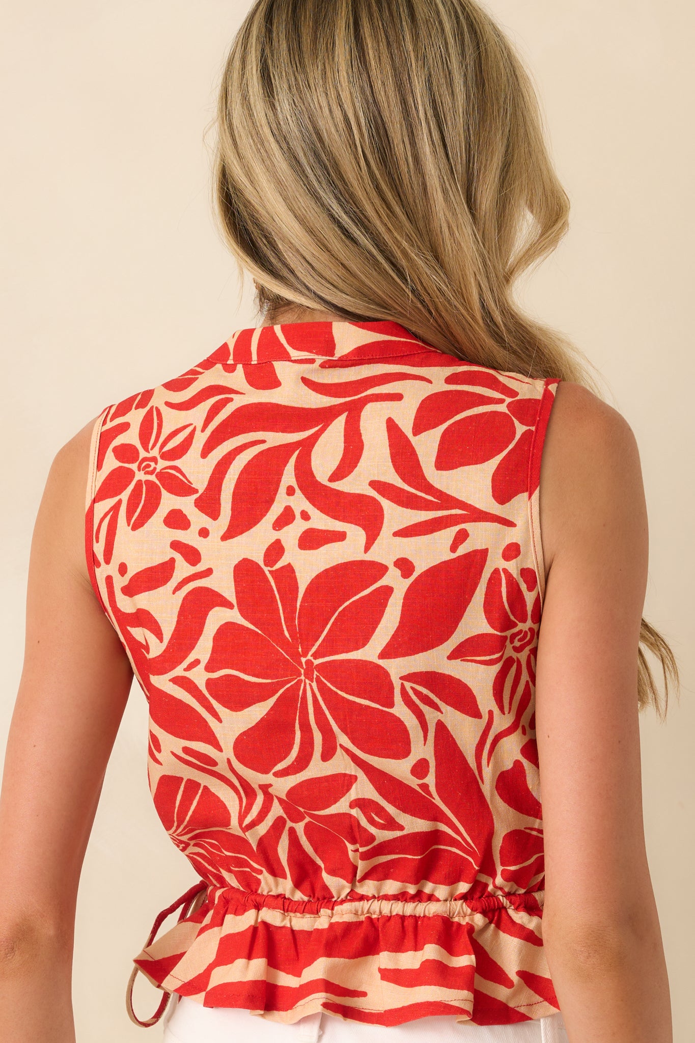A view from behind showing the continuous red and beige floral print and the gentle flare of the peplum hem.
