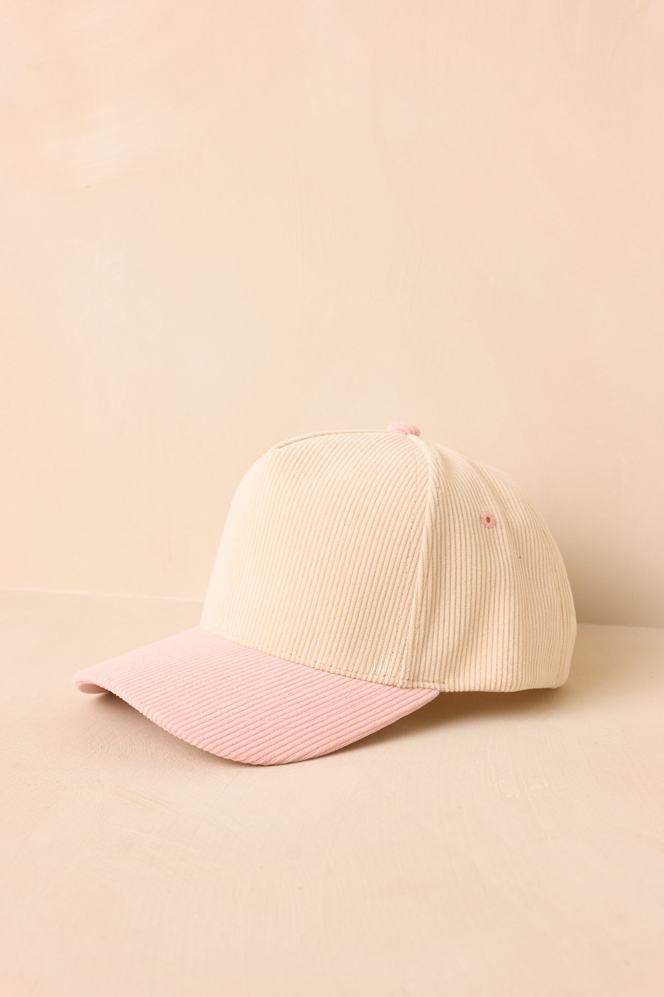 Beige and pink baseball cap on a beige background.