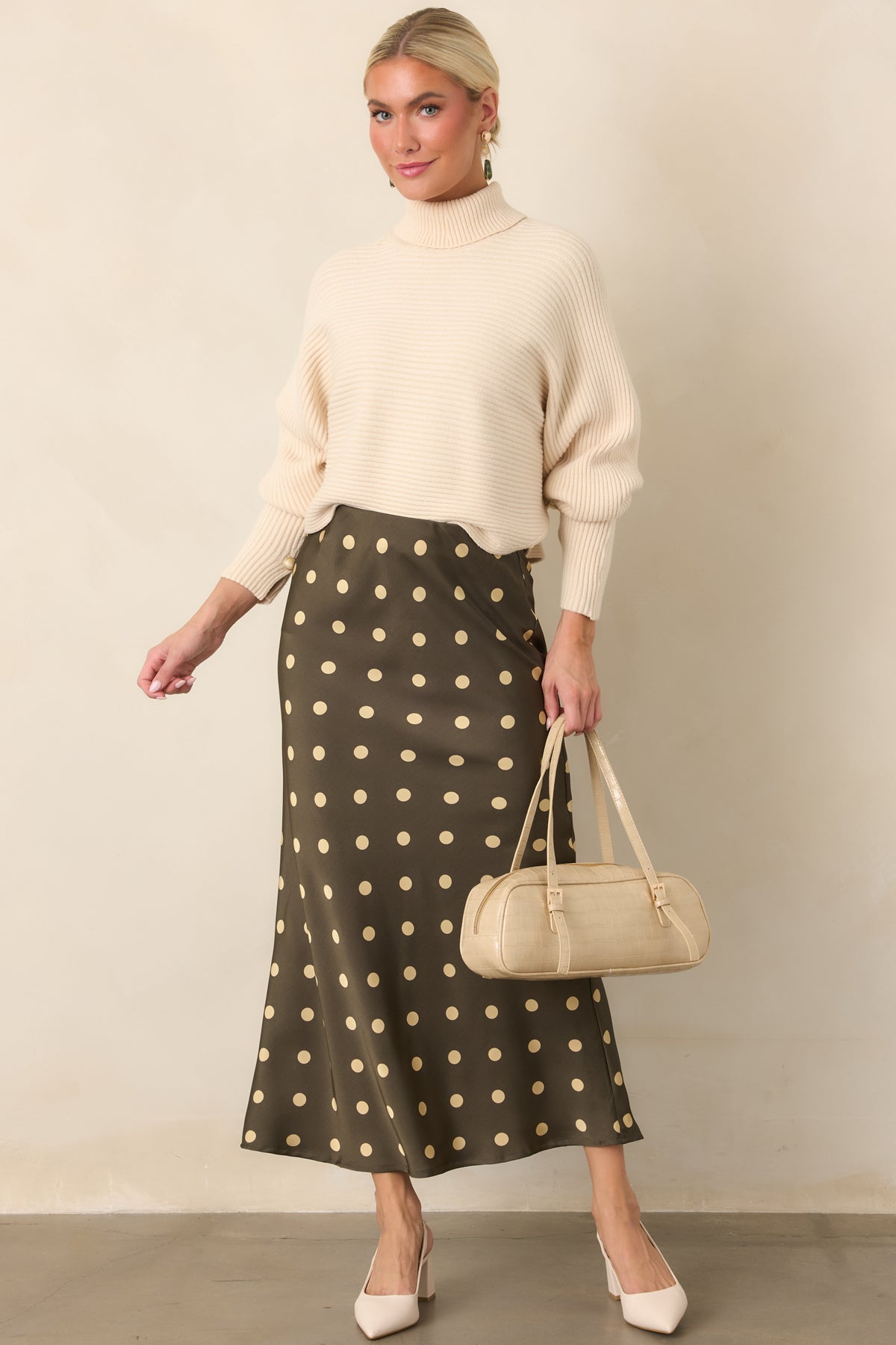 Cozy beige sweater with a softly draped batwing silhouette, ribbed knit texture, high turtleneck, and cropped length.