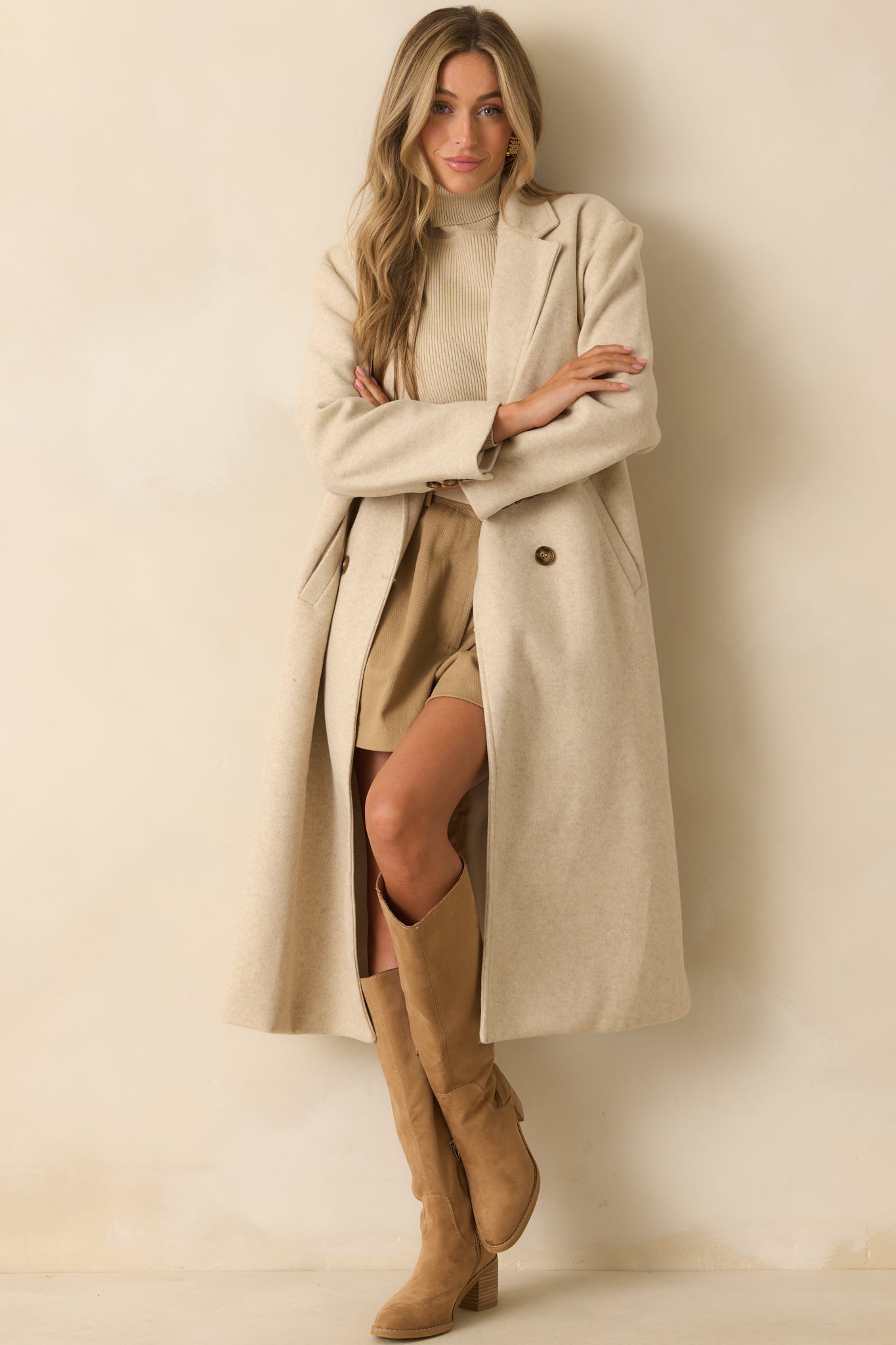 Beige coat featuring a longline silhouette, structured shoulders, and buttoned cuffs on the sleeves.