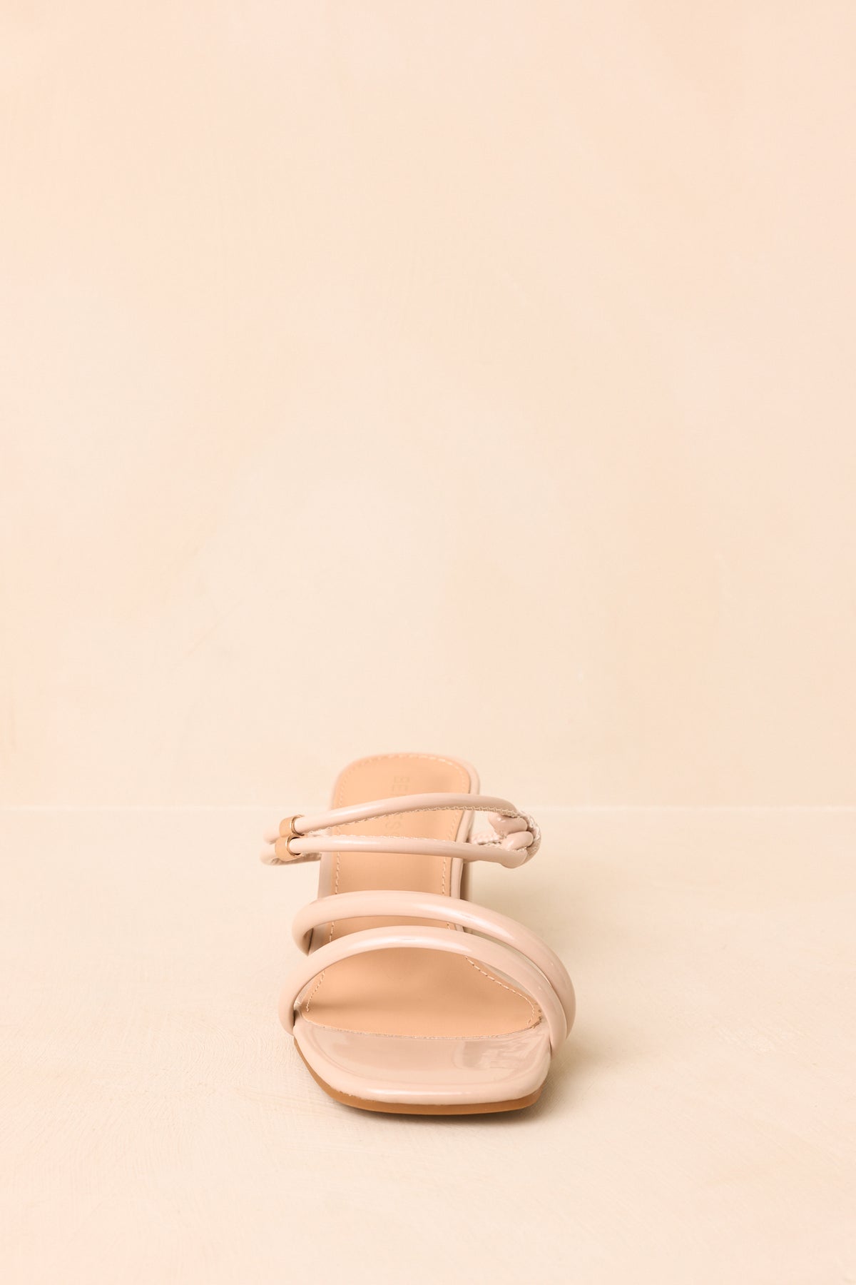 Beige heels showcasing the slender double strap across the instep with gold-tone detailing.